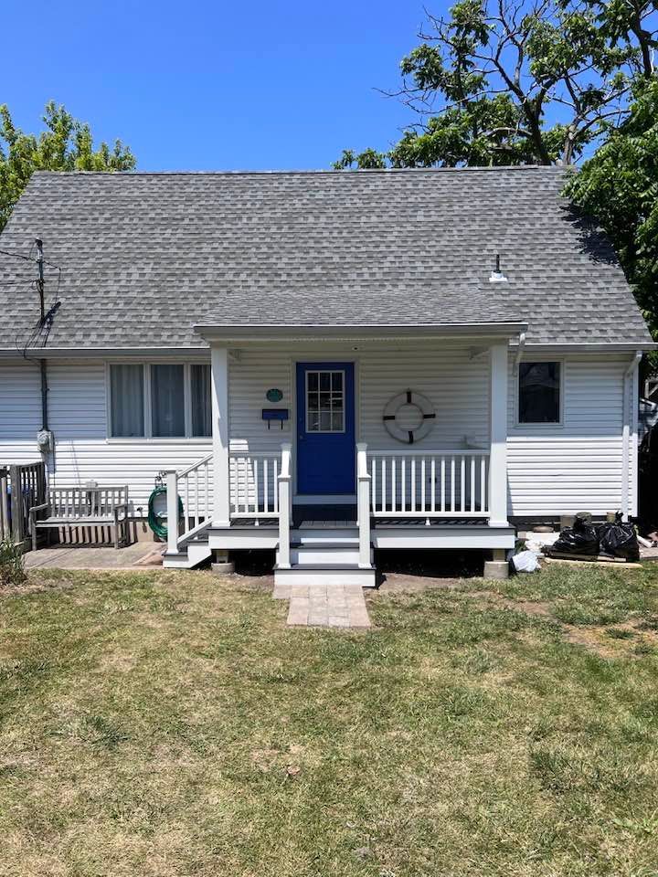 A small white house with a blue door and porch.