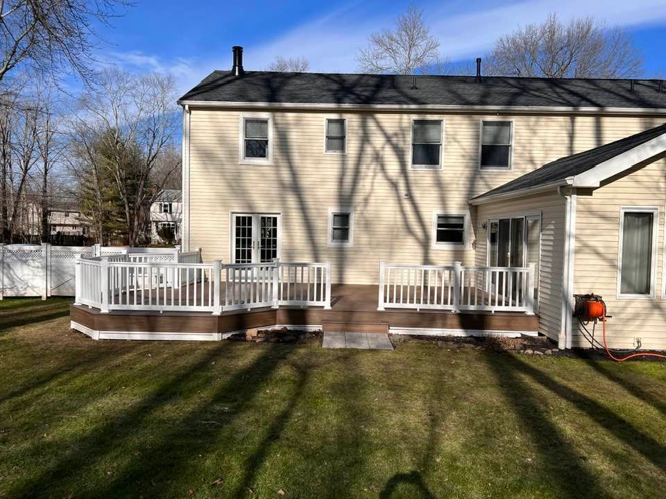 The back of a house with a large deck in the backyard.