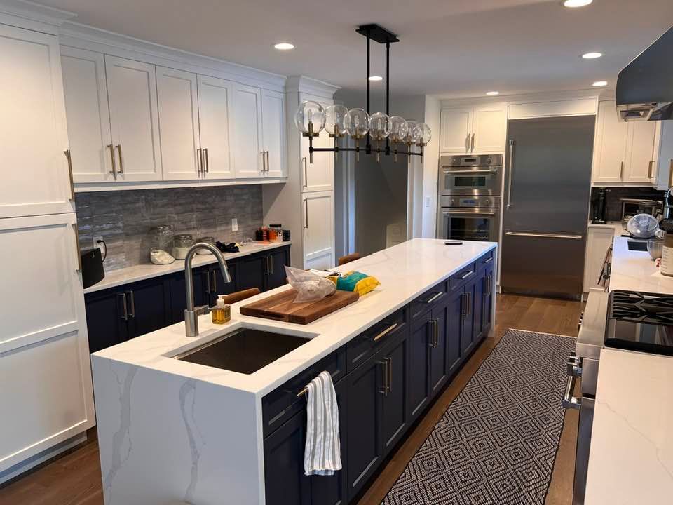 A kitchen with blue cabinets and white counter tops has a large island in the middle.
