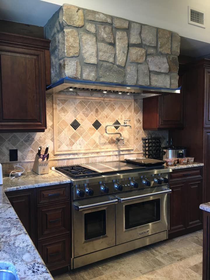 A kitchen with stainless steel appliances and a stone wall