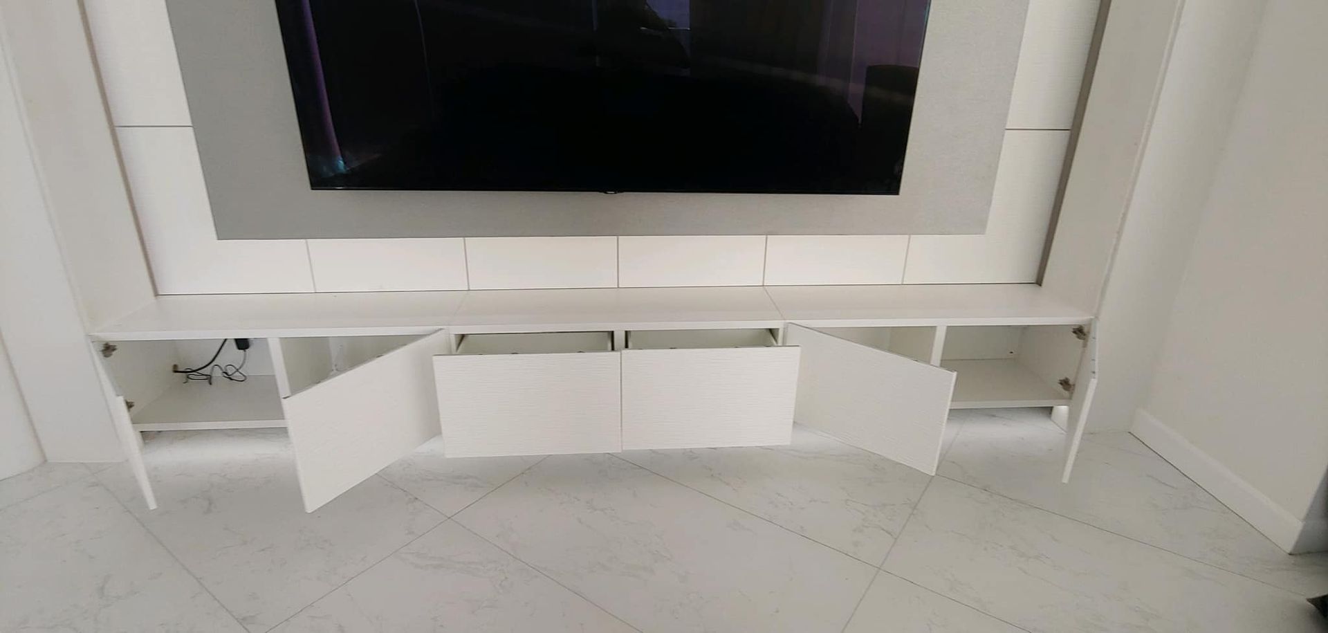 A white entertainment center with a flat screen tv mounted to the wall.