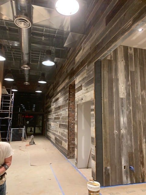A man is standing in a hallway with wood paneling on the walls.