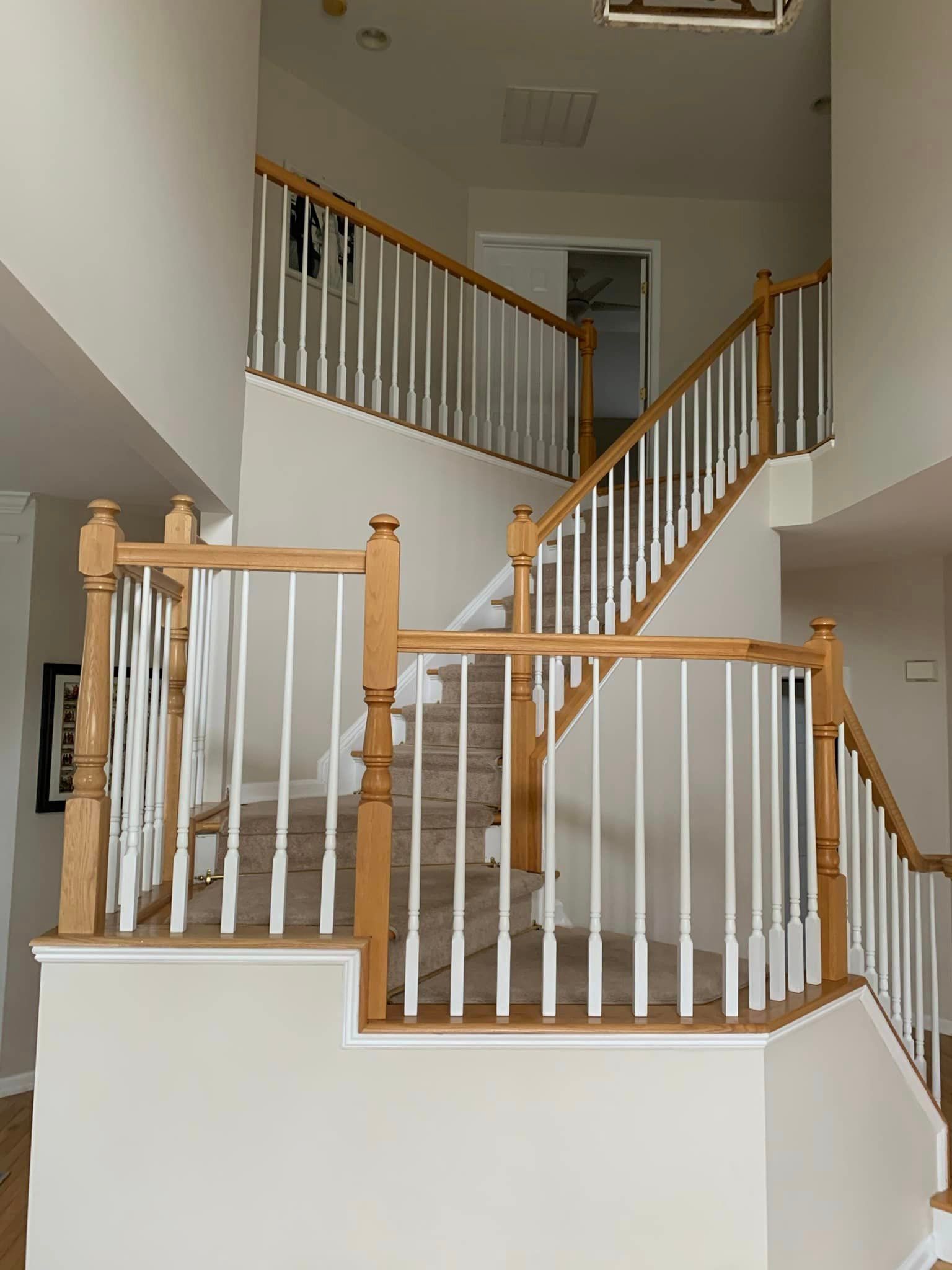 A staircase with a wooden railing and white railings