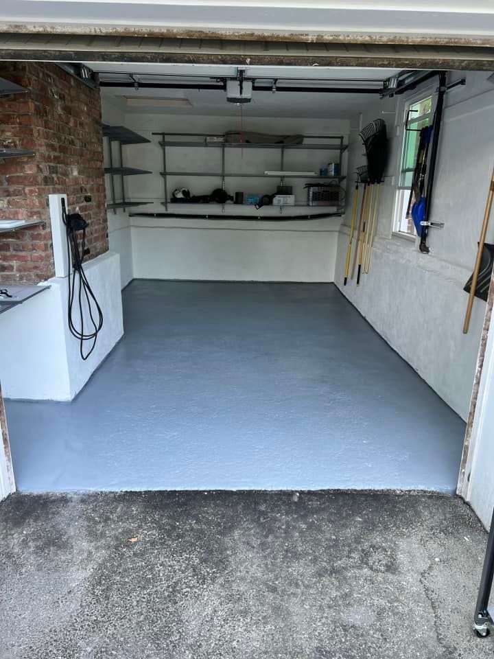 A garage with a gray floor and a brick wall.