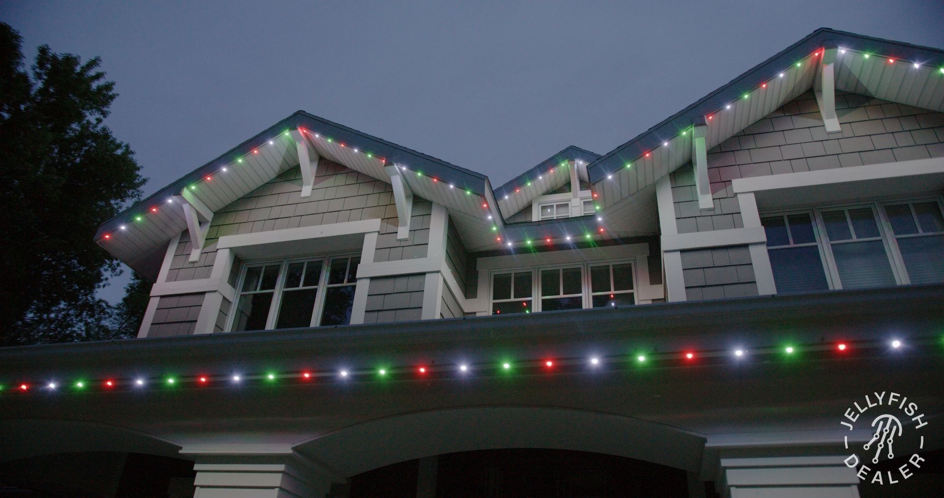 Close-up of a Craftsman-style home roofline outlined with JellyFish permanent holiday lights in red,