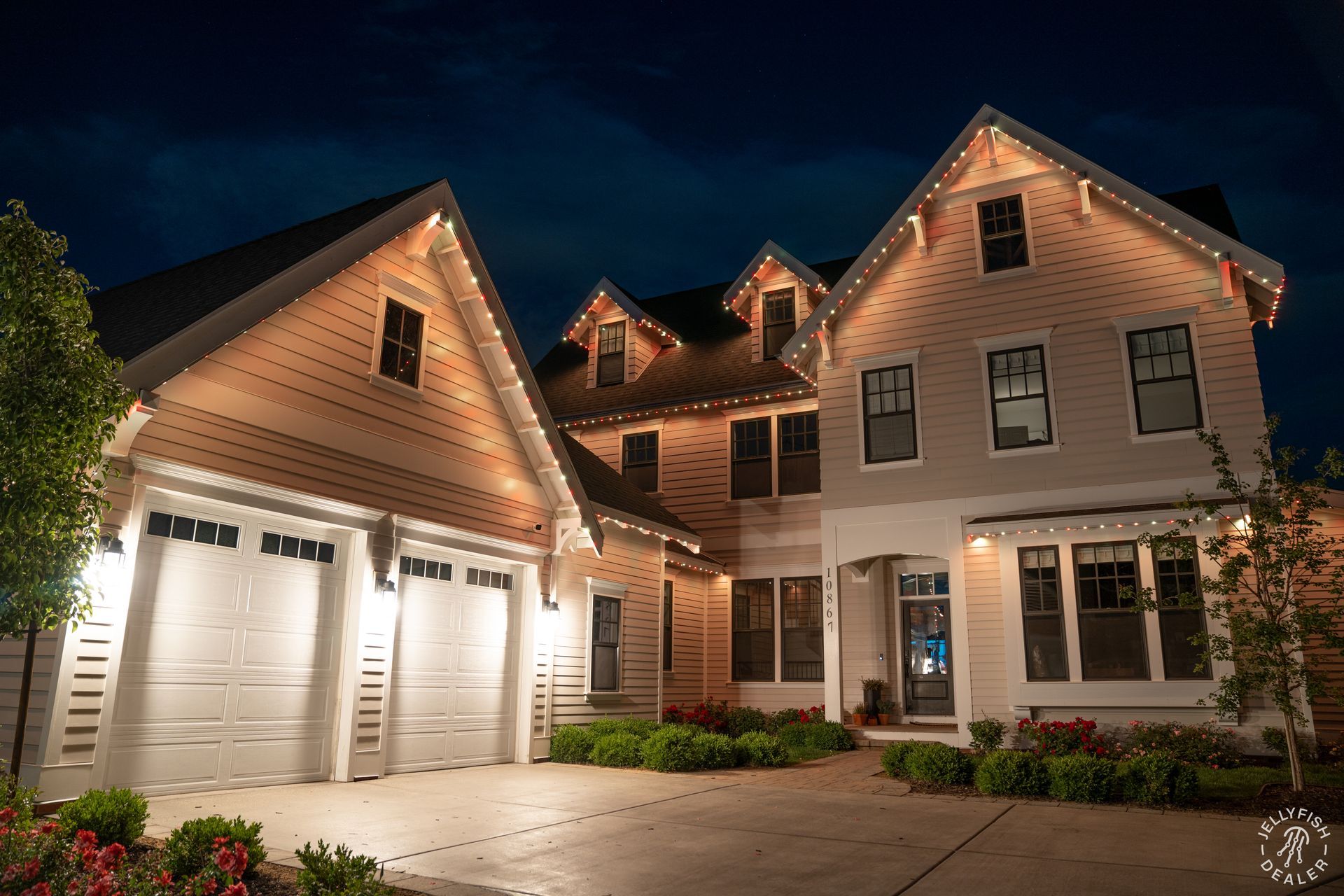 Two-story home glowing with warm white and soft red JellyFish Lighting along the roofline.