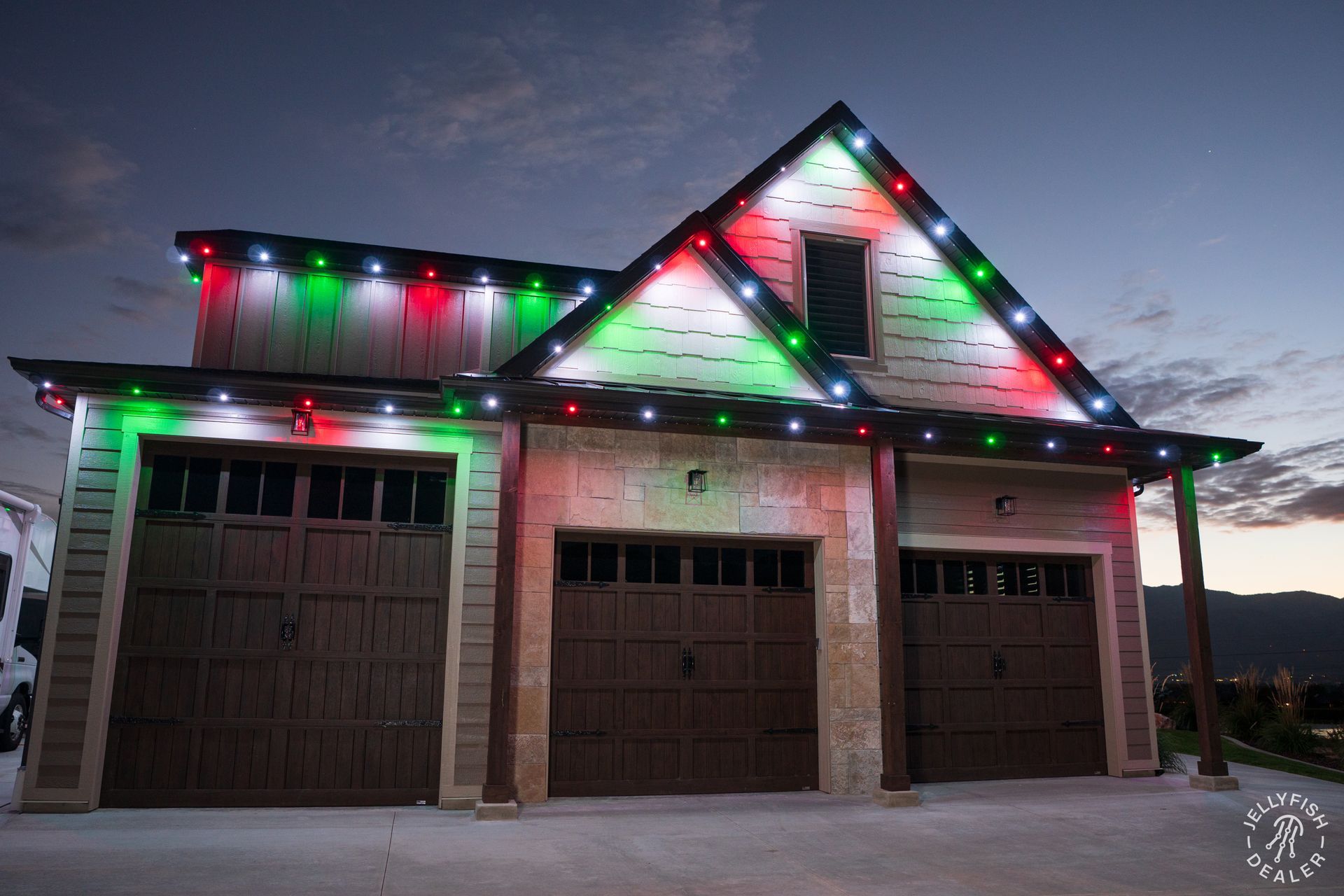 Bonney Lake roofline and garage outlined with JellyFish permanent Christmas lights in red, green, and white at dusk.