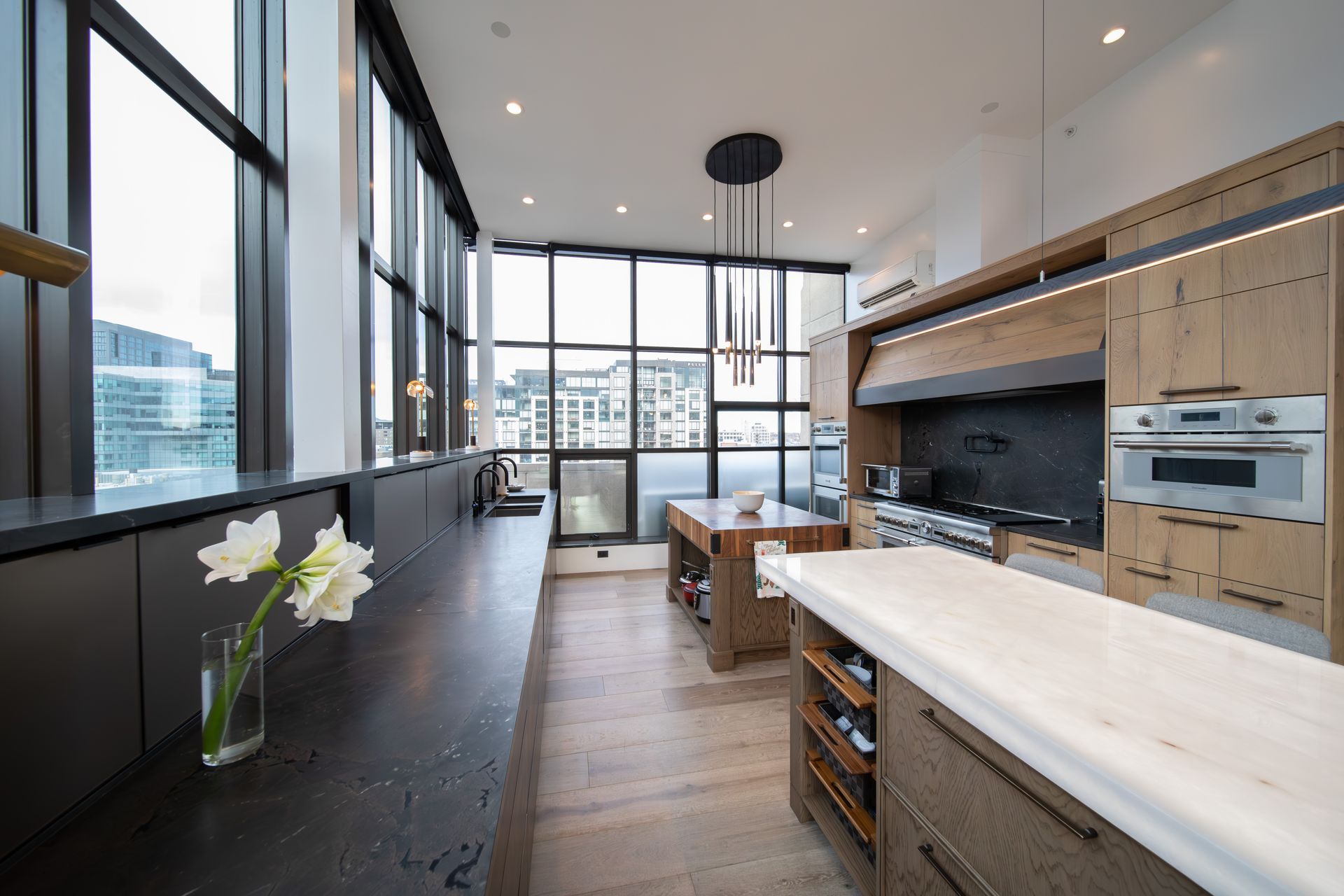 Open-concept modern home interior with large windows, high ceilings, and connected living and kitchen spaces.