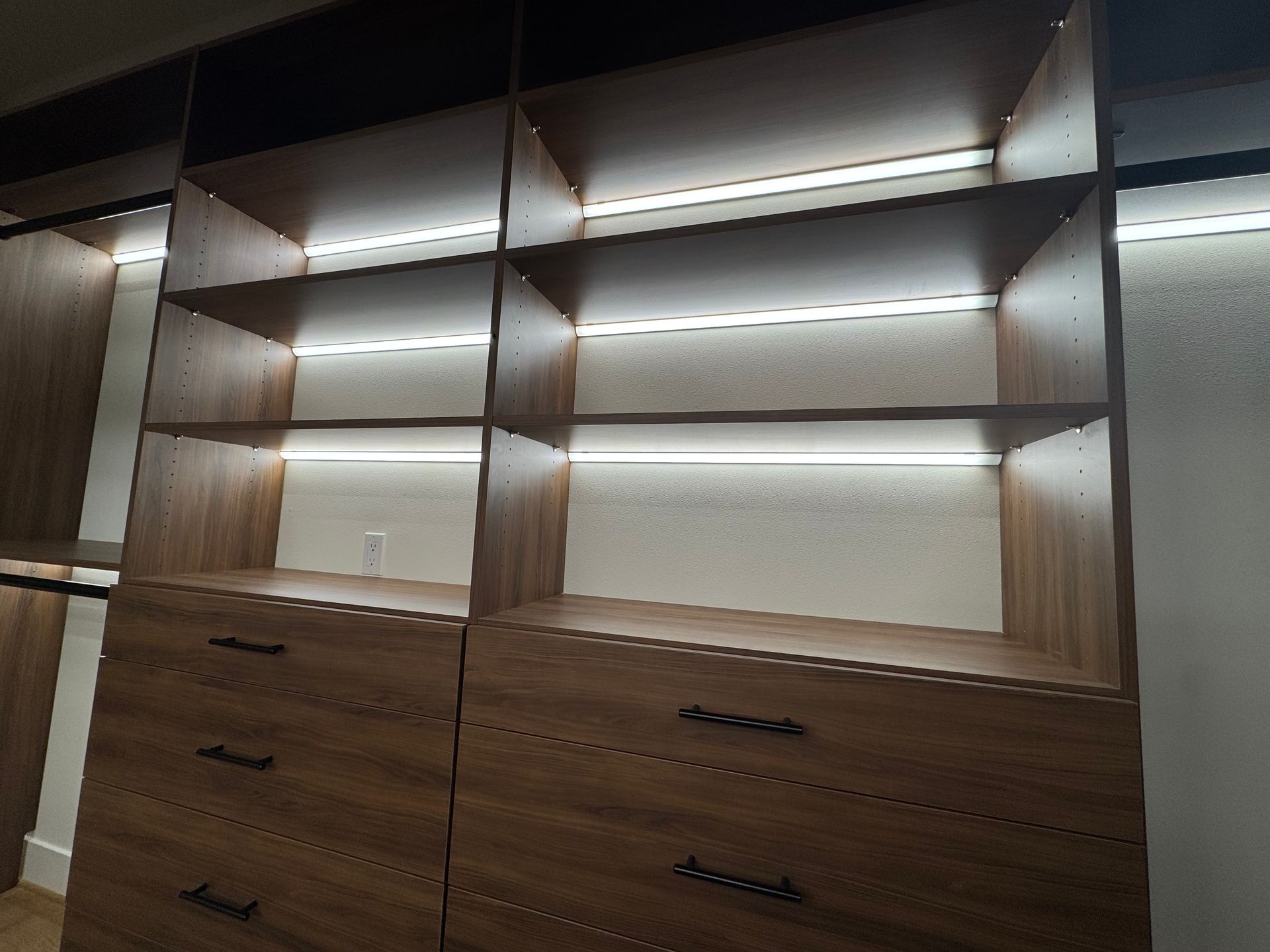 Installed master closet with integrated Colorbeam LED lighting illuminating shelving and storage spaces.