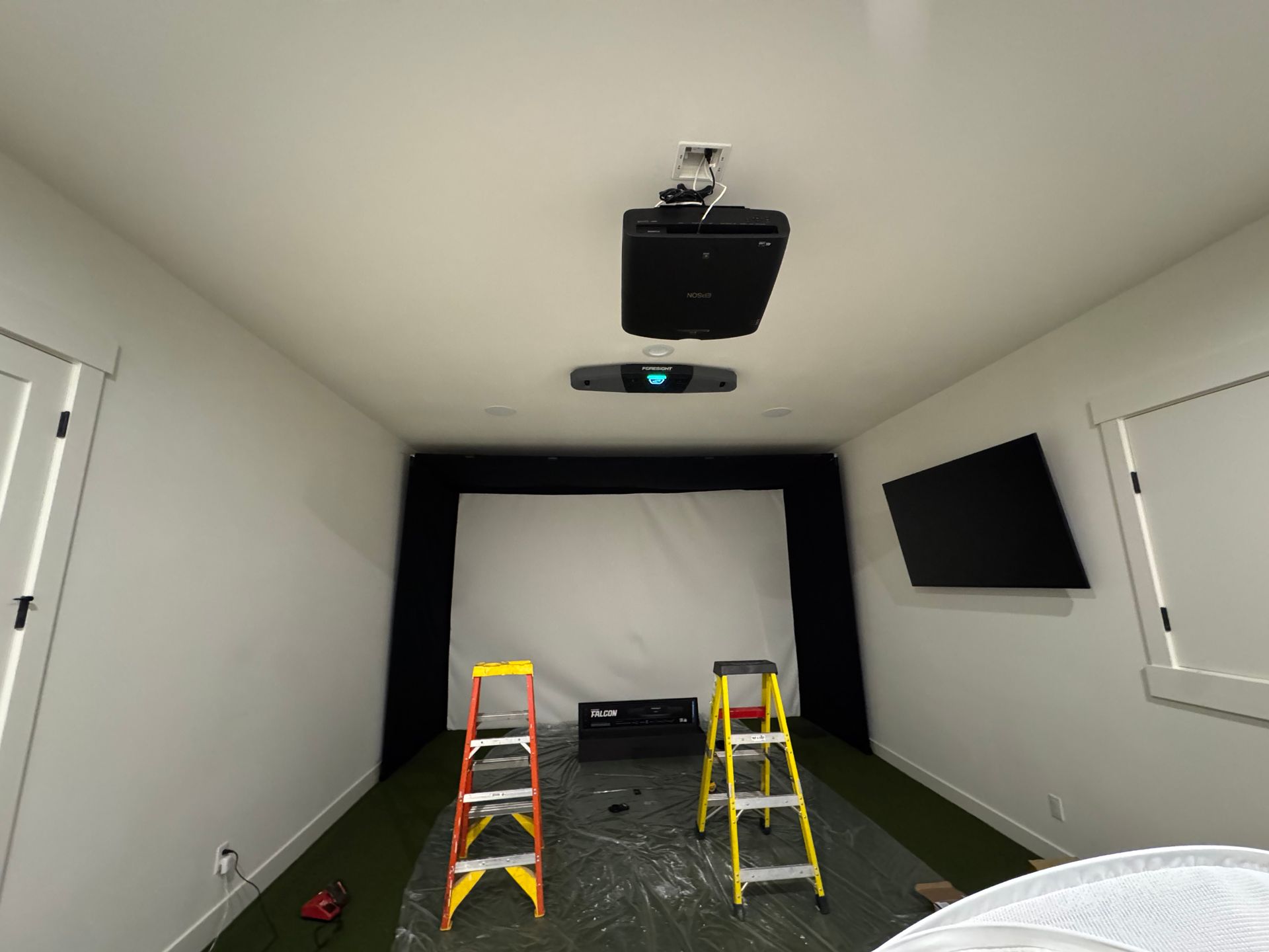 Ceiling-mounted short-throw projector and Foresight GCHawk launch monitor during installation