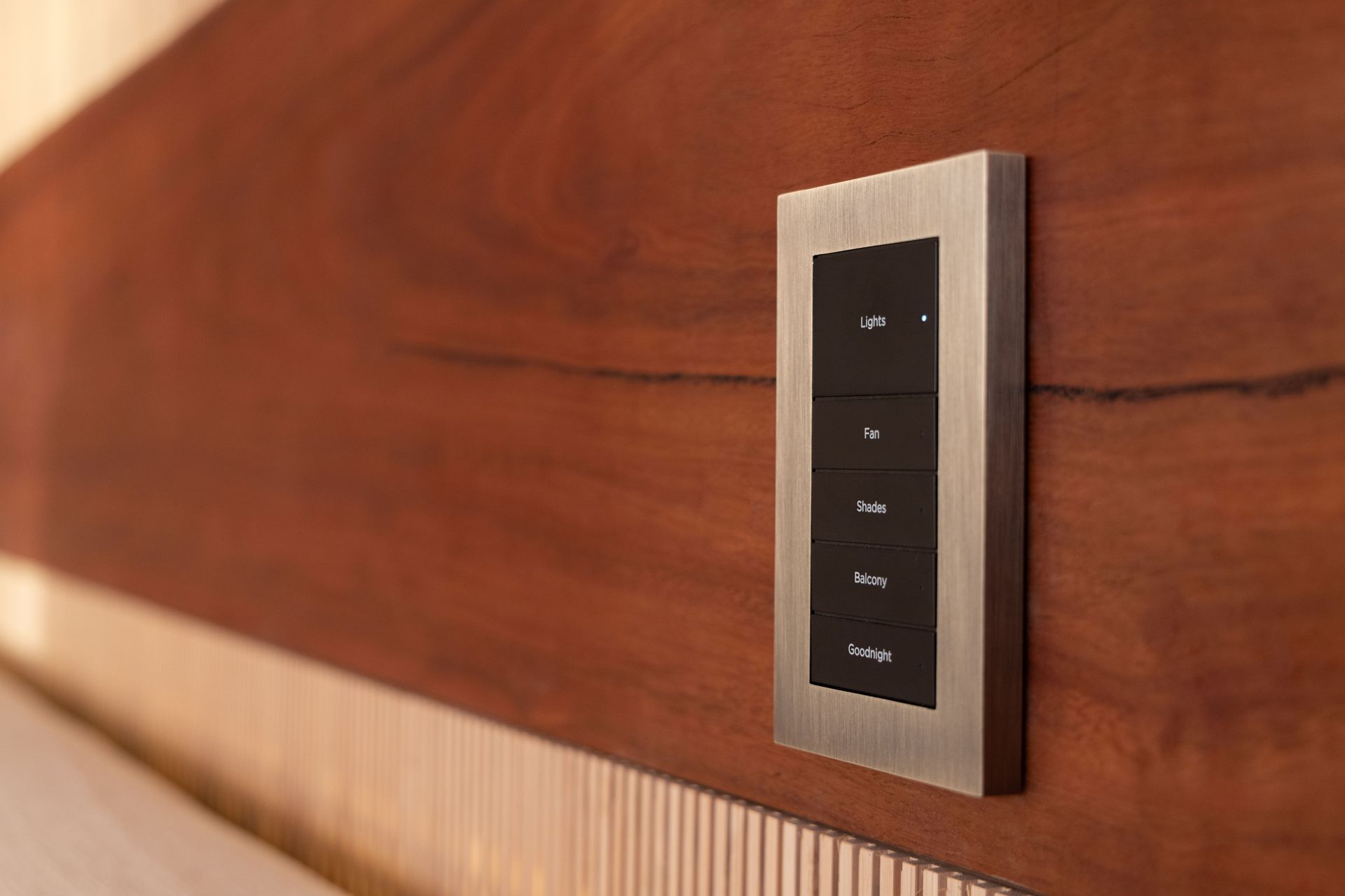 Wall-mounted smart lighting keypad on a wood accent wall in a home theater, showing preset scene buttons.