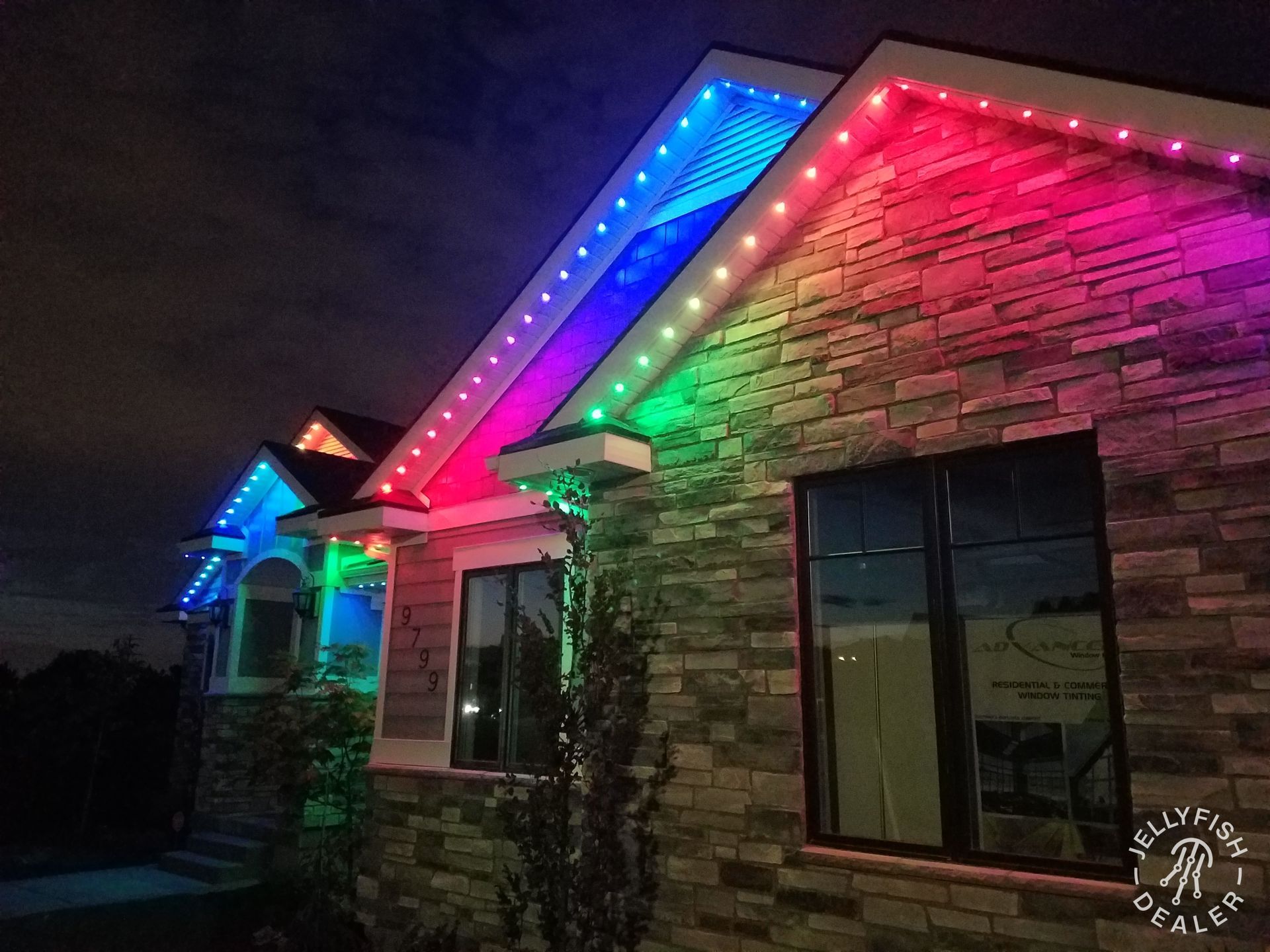 Bonney Lake home with JellyFish permanent holiday lighting installed along the roofline, showing bright multi-color scenes on gables and eaves.