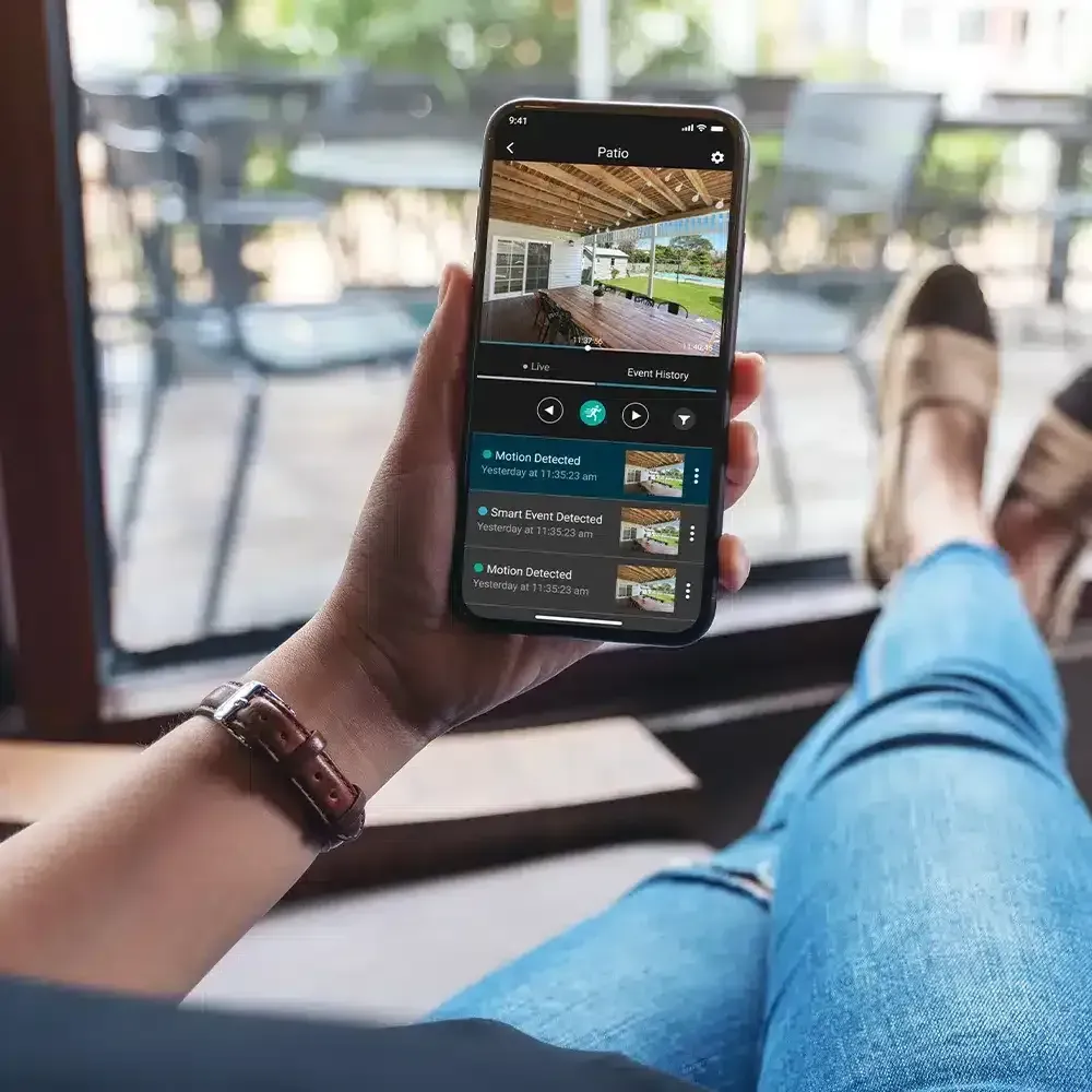 Person holding a smartphone displaying a security camera feed.