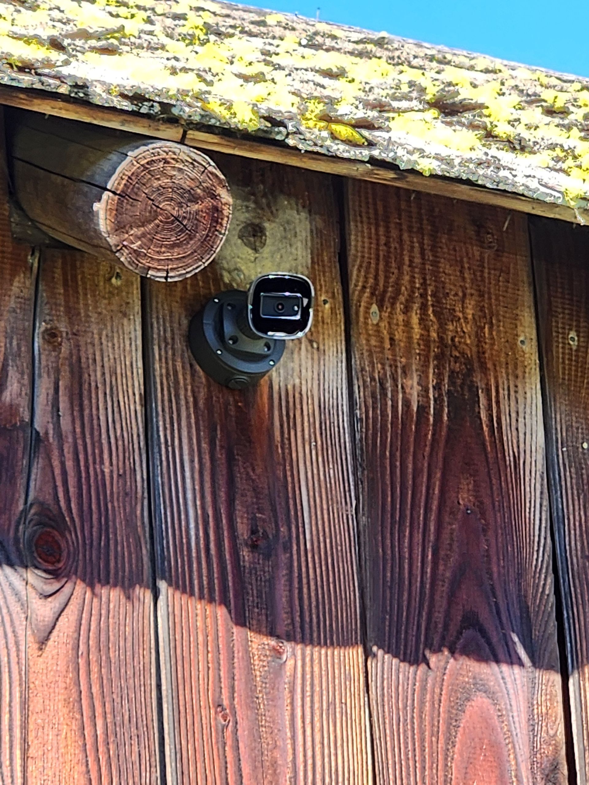 AI surveillance camera blended into weathered barn siding on a South Sound estate