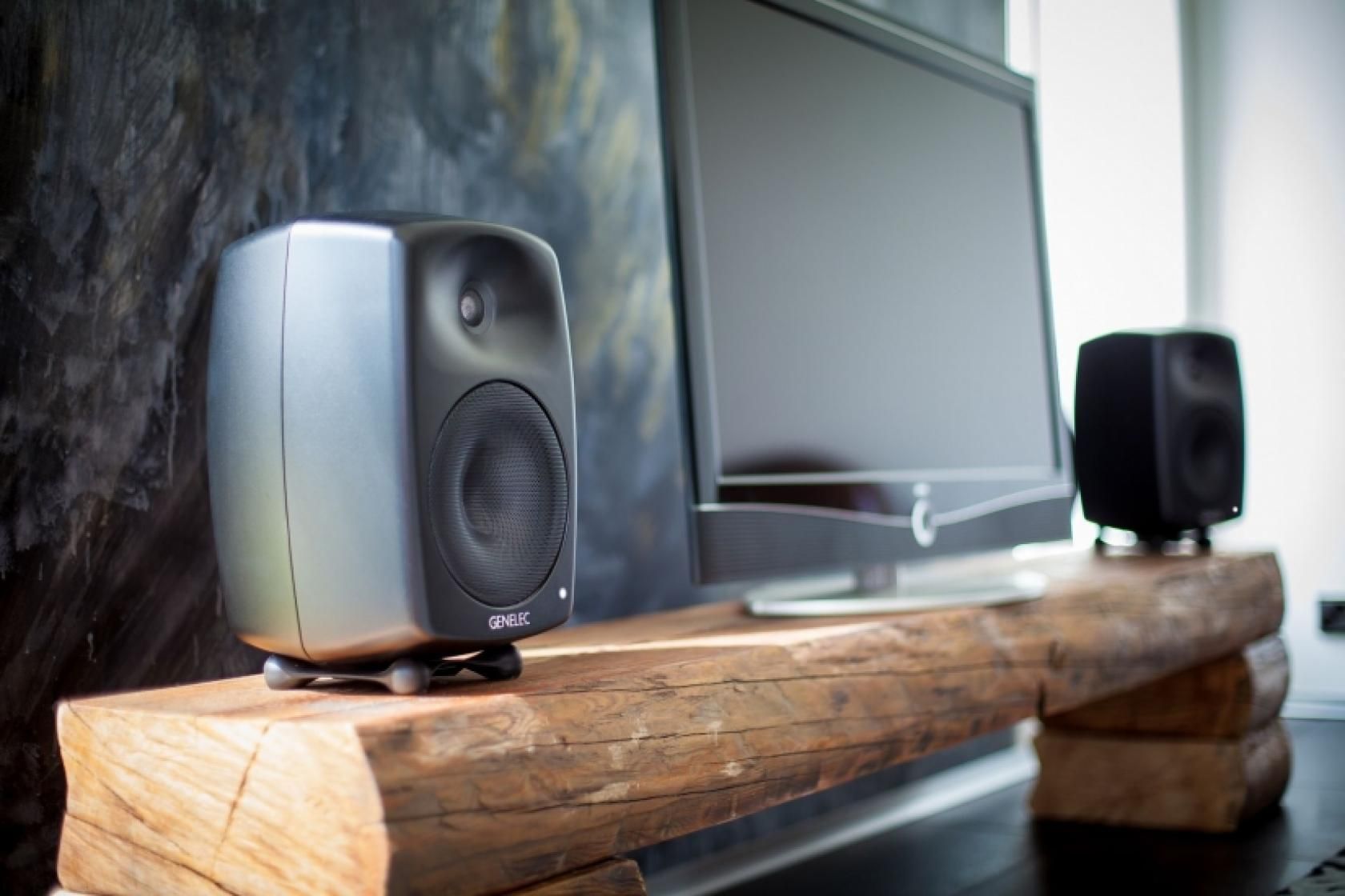 Genelec powered speakers paired with a minimalist TV setup, delivering studio-quality sound for home entertainment systems by Rivas Technology Group.