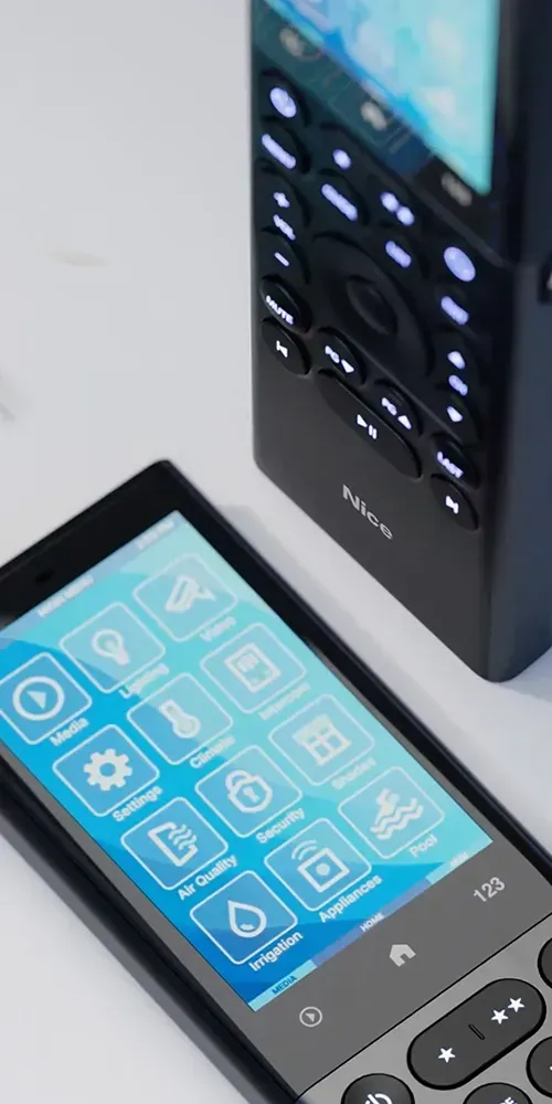 Two black remote controls on a white surface, one with a touchscreen showing icons, the other with buttons.