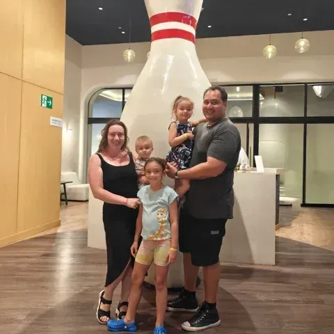 A family is posing for a picture in front of a large bowling pin.