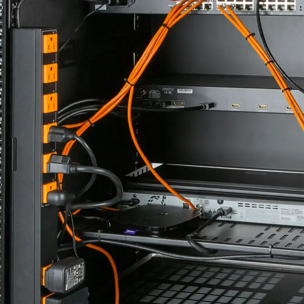 Black server rack with orange power outlets, cables, and network equipment.