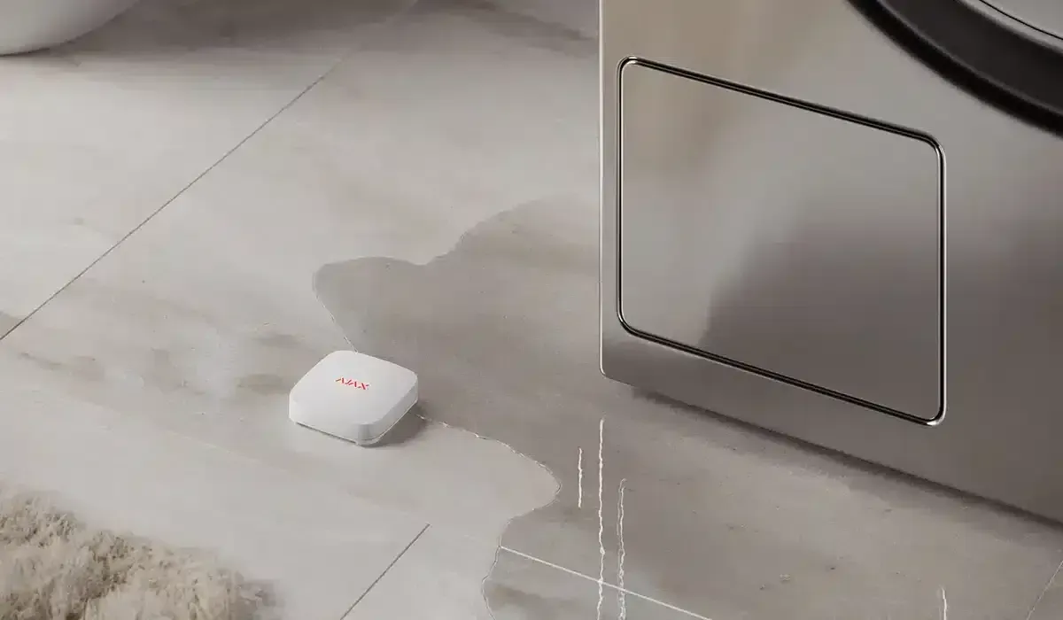 Water leak sensor on wet floor next to a washing machine.