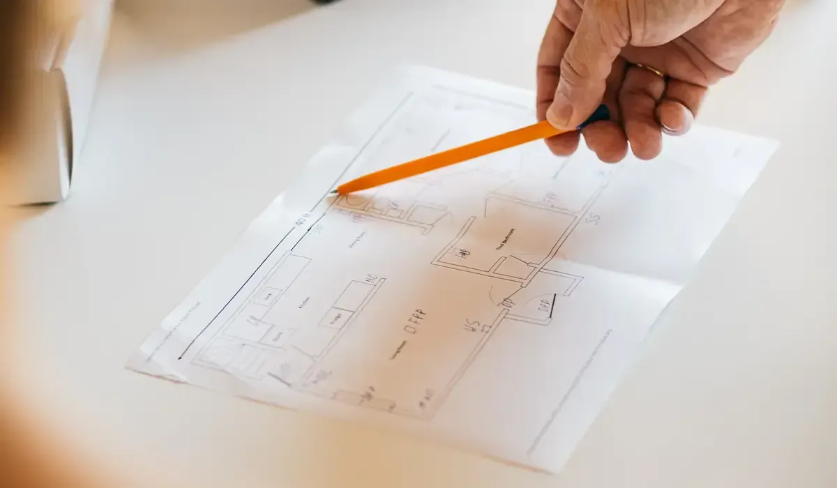 A person is holding a pencil over a piece of paper.