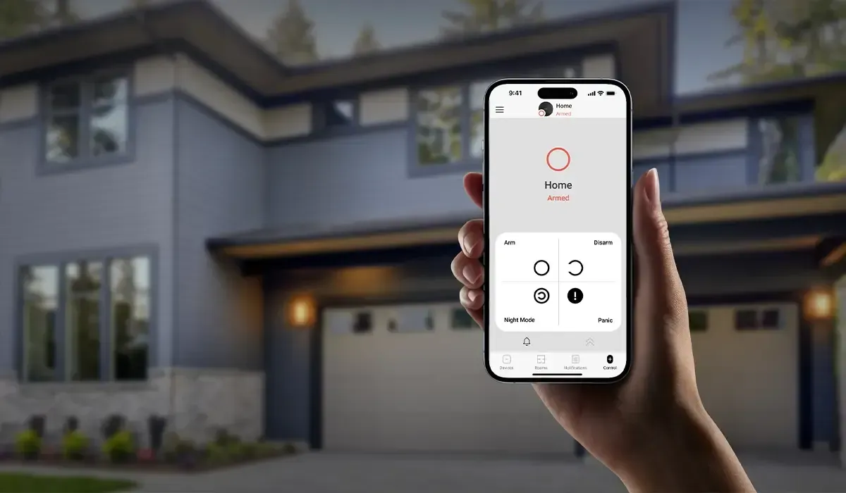 A person is holding a smart phone in front of a house.
