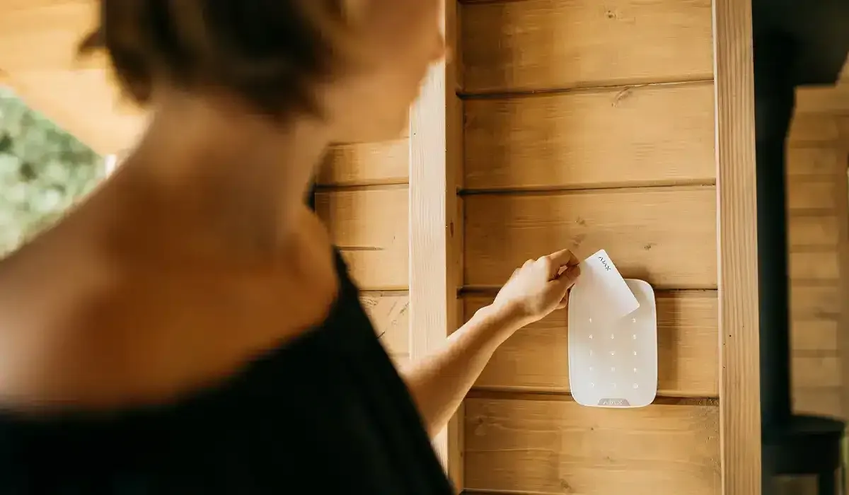 A woman is holding a bottle of milk against a wooden wall.