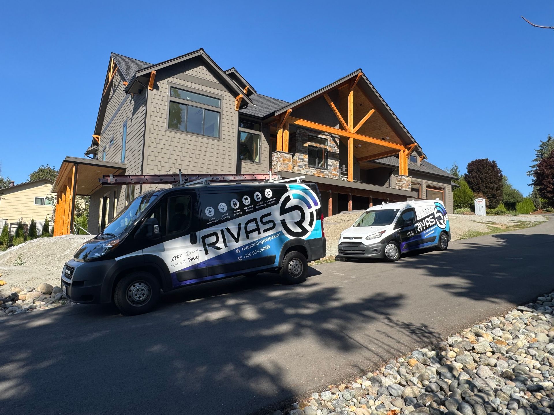 Rivas Technology Group service vans parked outside a large modern home during a smart home installation in the South Sound.