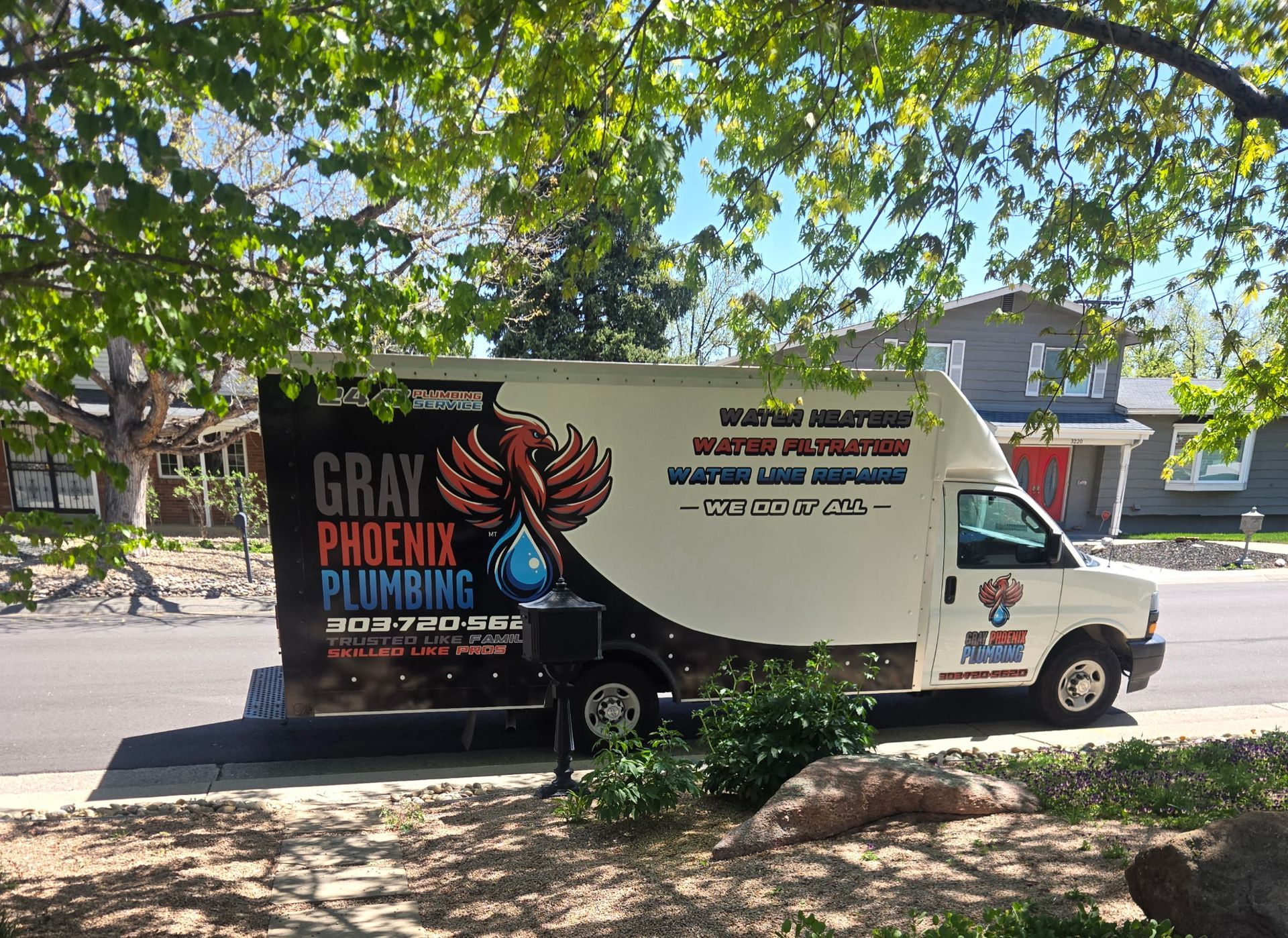 A gray phoenix plumbing truck is parked on the side of the road