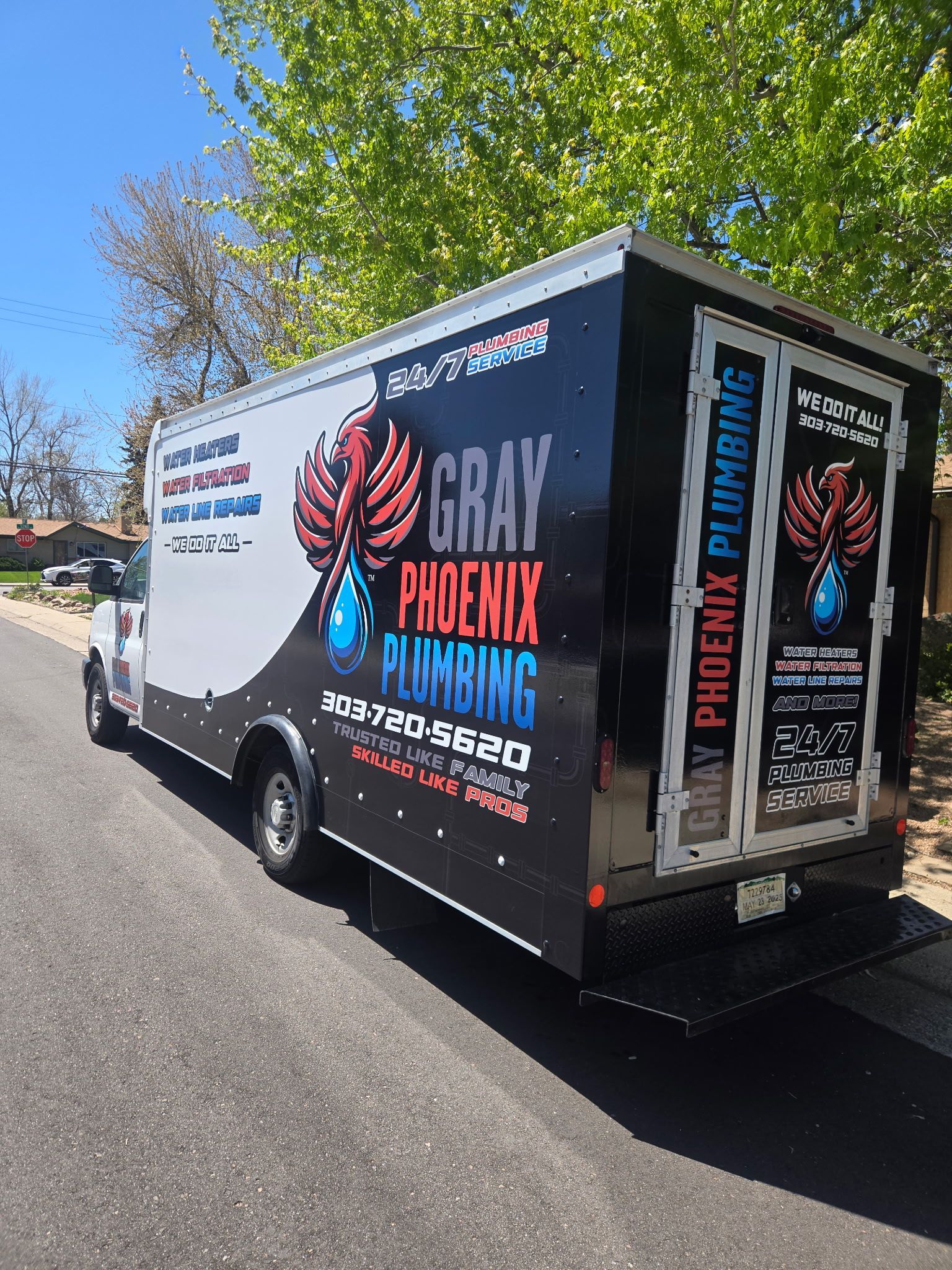 A gray phoenix plumbing truck is parked on the side of the road.