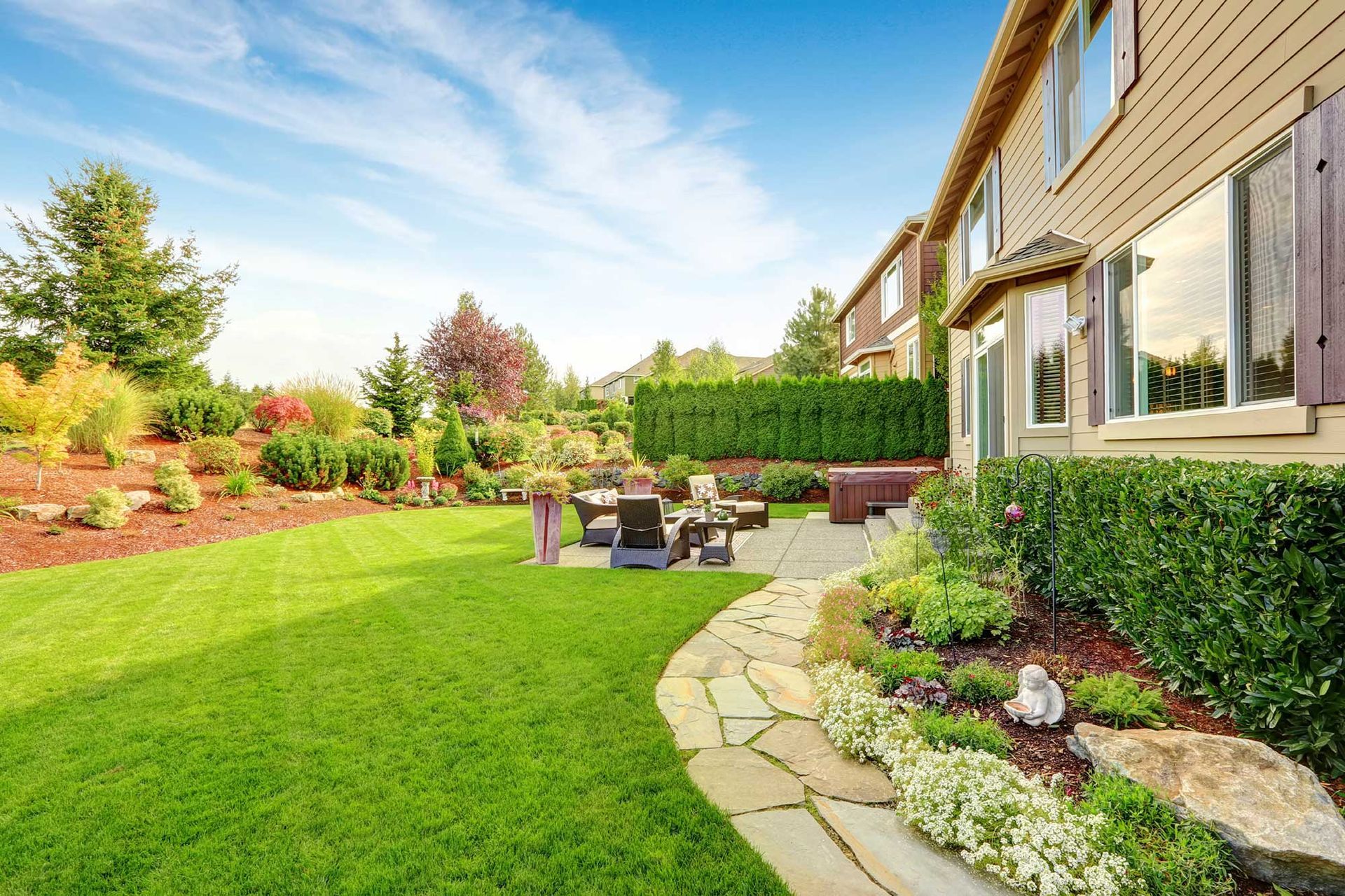 A large house with a lush green lawn and a stone walkway leading to it.