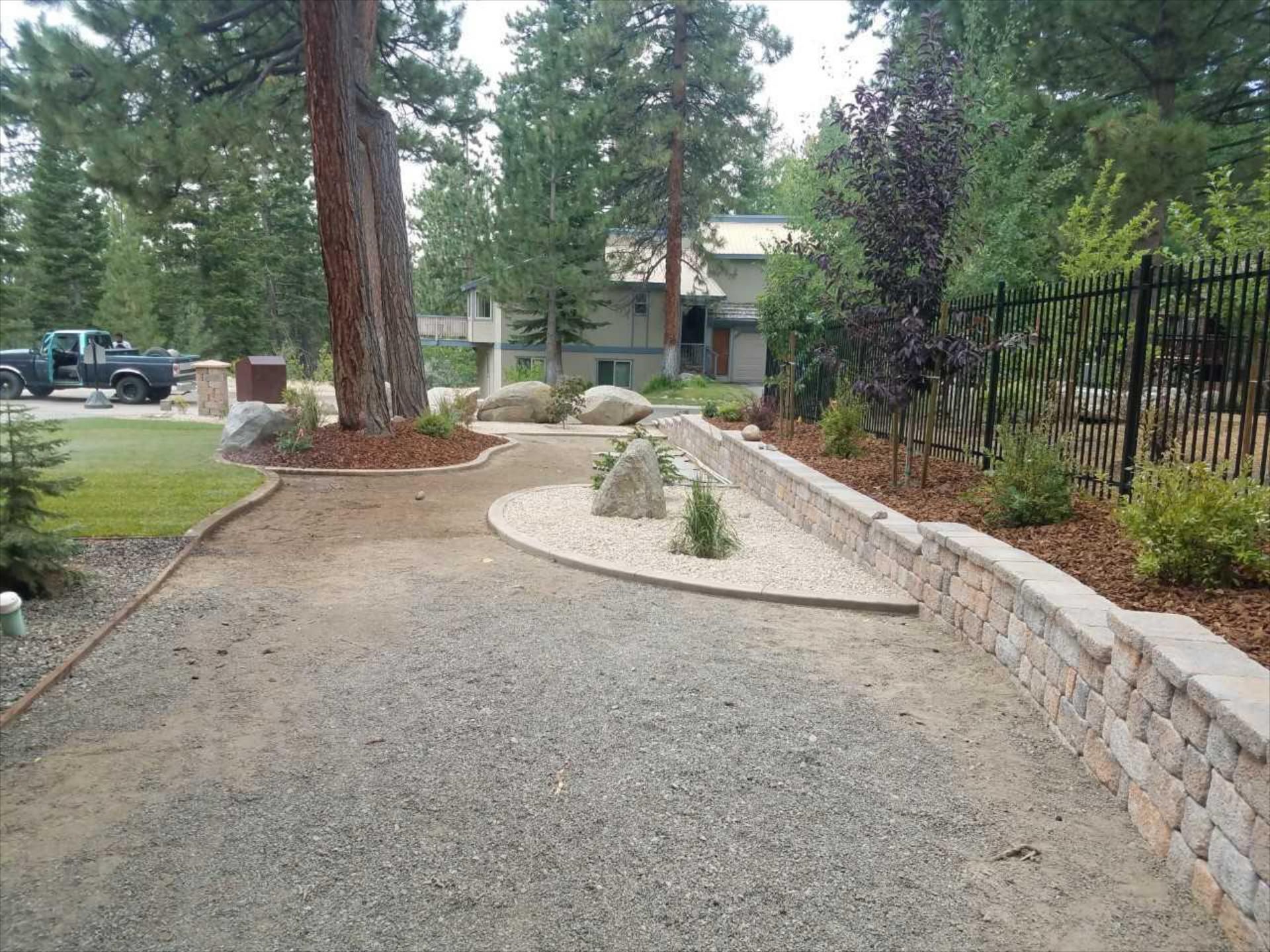 A gravel driveway leading to a house with a fence