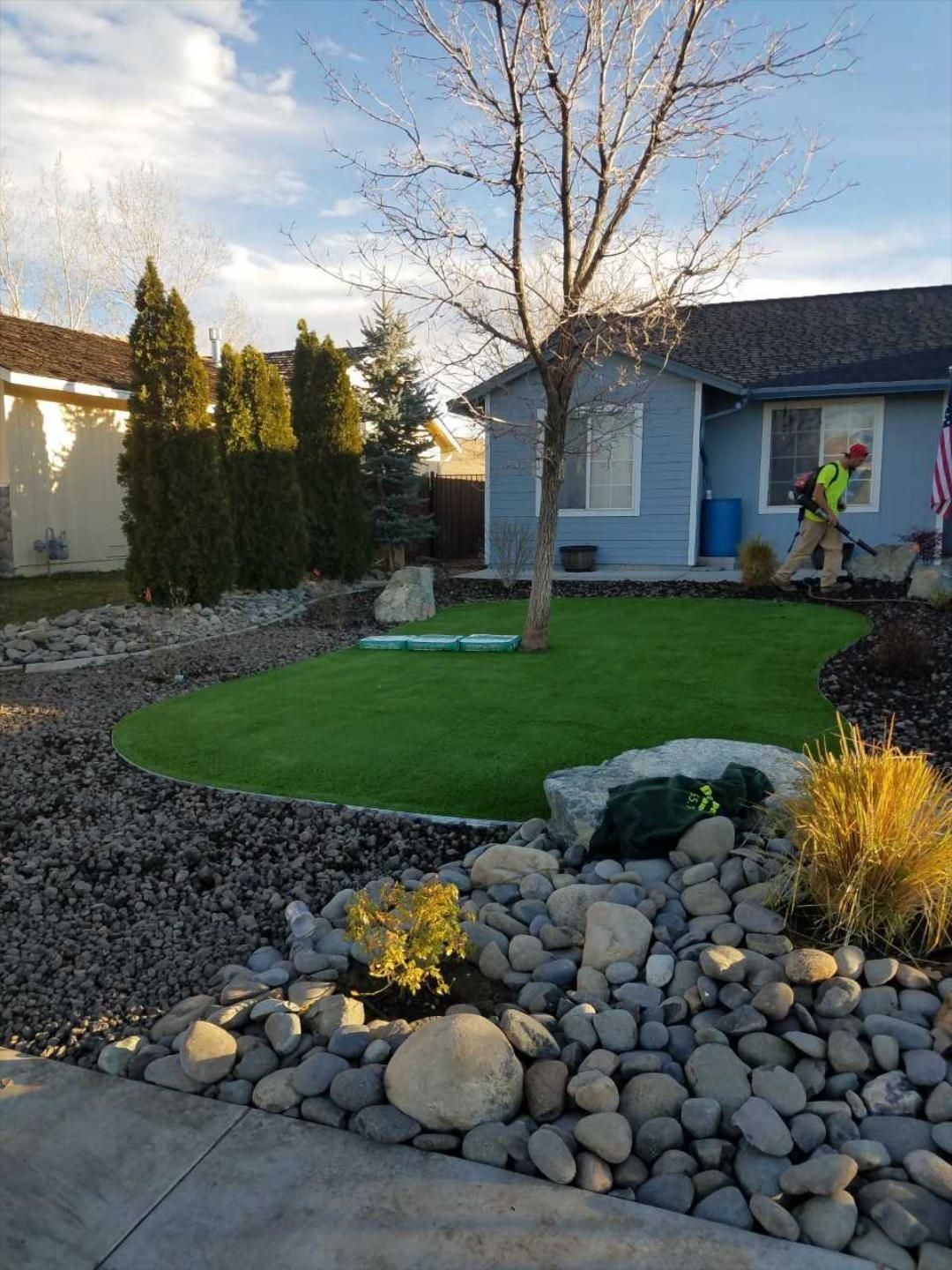 A man is working on a lawn in front of a house.