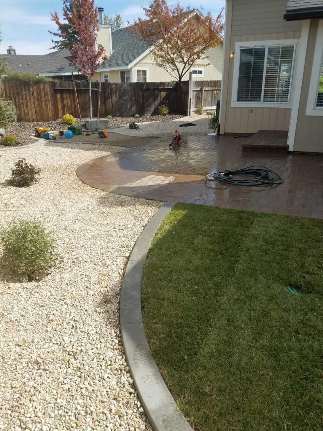 A backyard with a patio and a house in the background.
