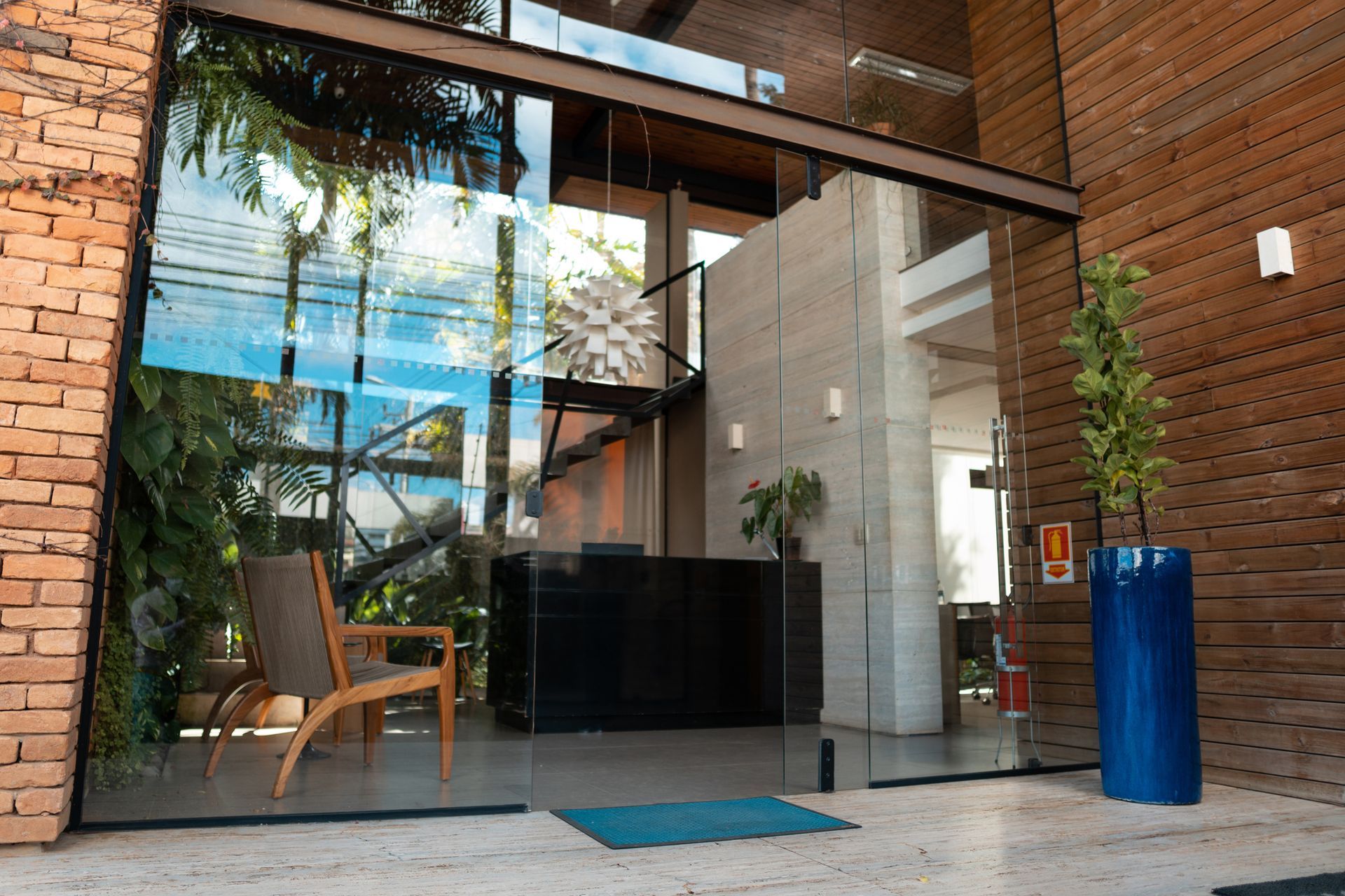 Glass door with a potted plant beside it, showcasing a modern storefront glass installation. Glass door with a potted plant beside it, showcasing a modern storefront glass installation.