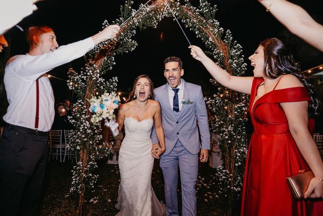 A bride and groom are walking through a tunnel of sparklers.