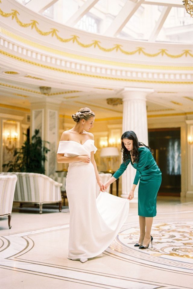 A woman is helping a bride get ready for her wedding.