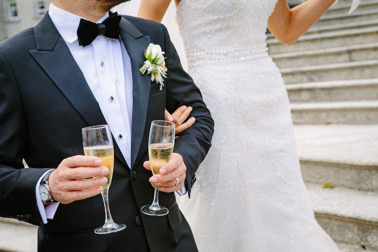 A bride and groom are holding champagne glasses in their hands.