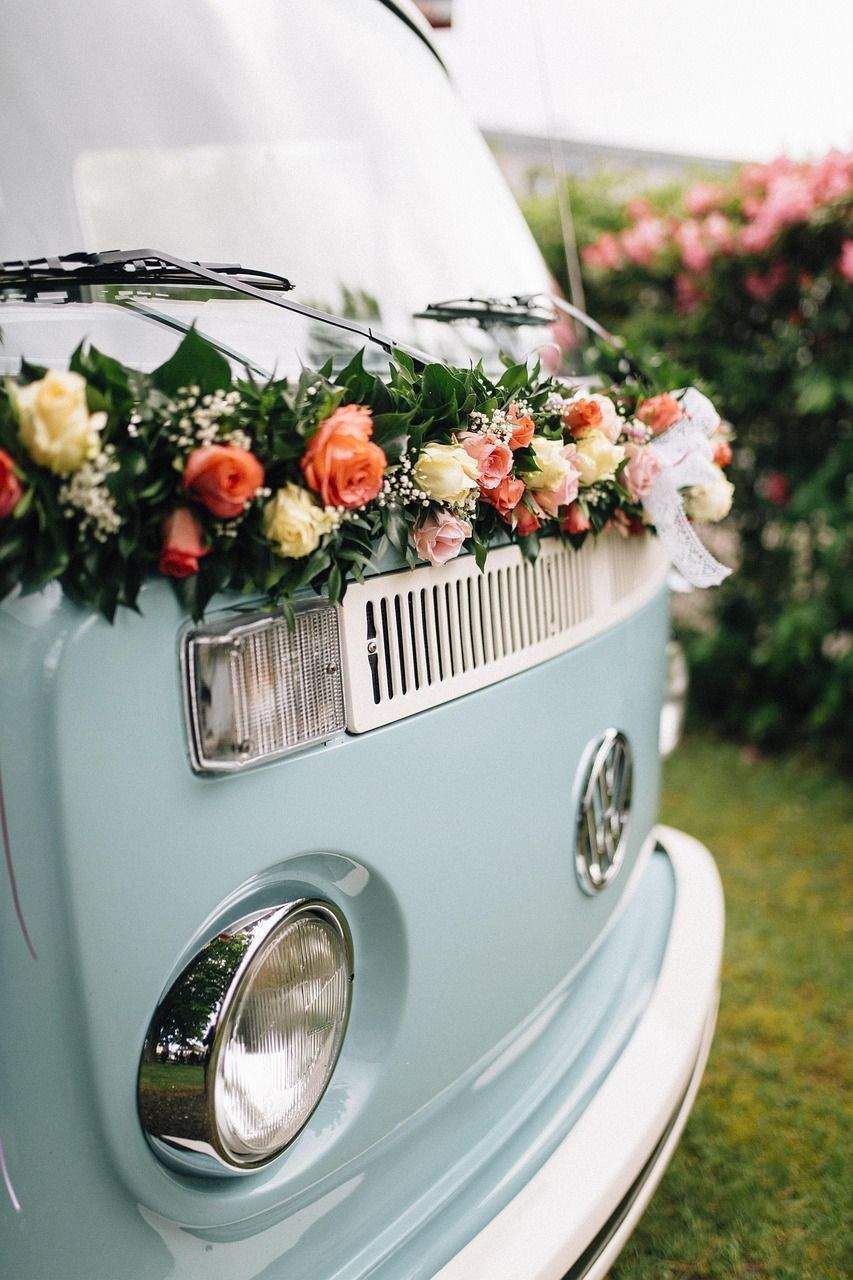 The front of a blue van decorated with flowers.