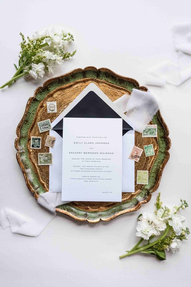 A wedding invitation is sitting on top of a wooden tray surrounded by flowers.