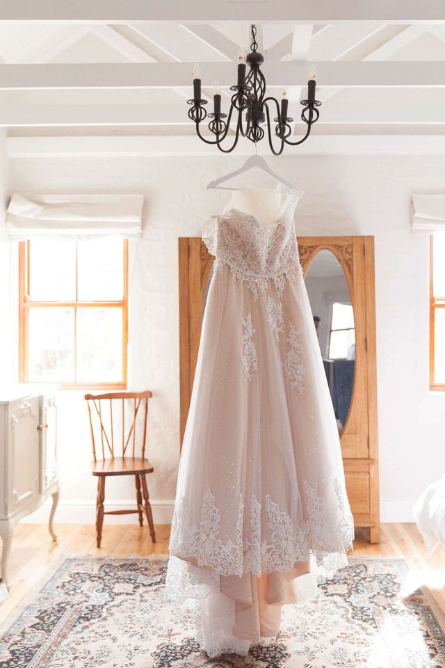 A wedding dress is hanging from a chandelier in a room.