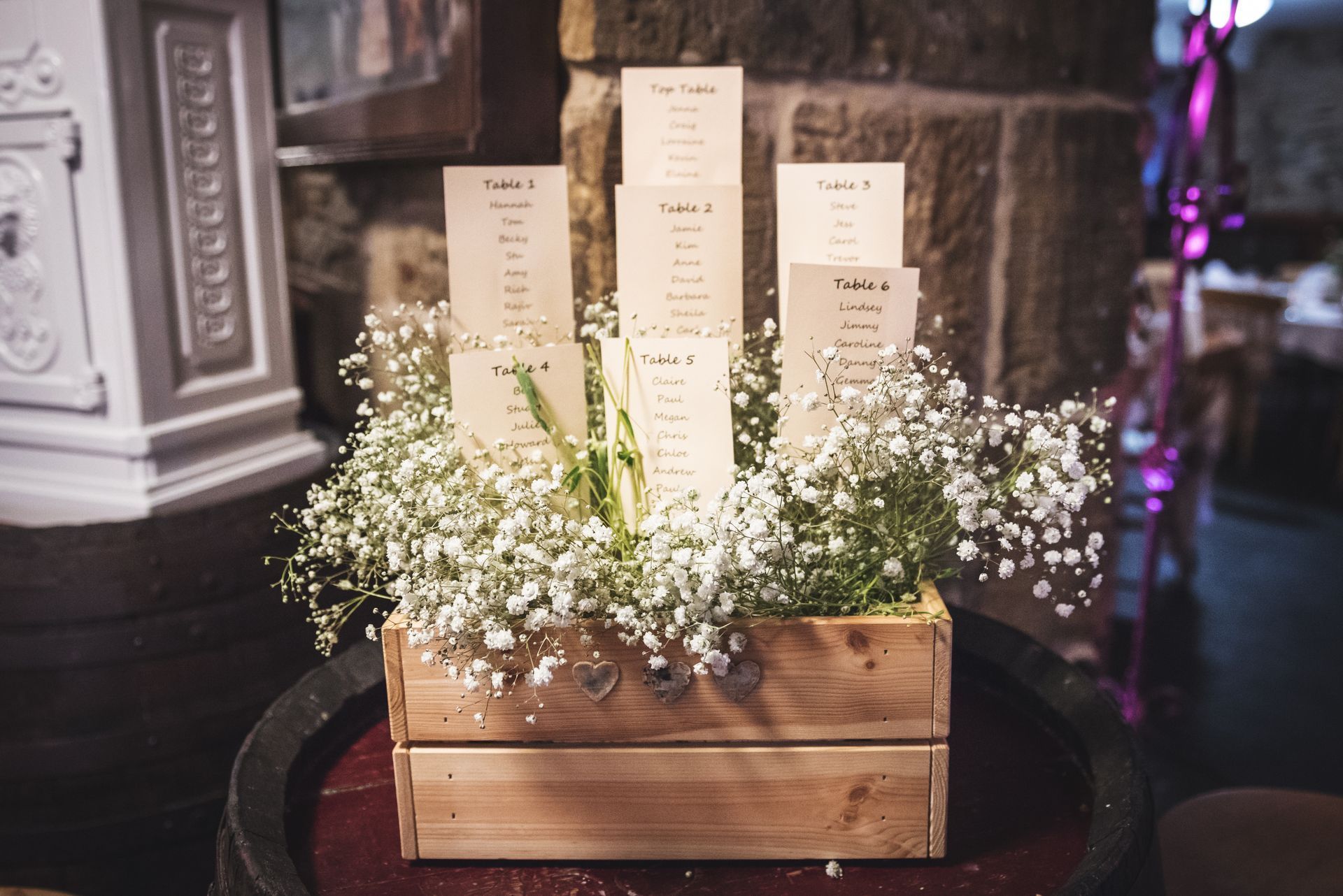 A wooden box filled with baby 's breath and cards is sitting on top of a wine barrel.