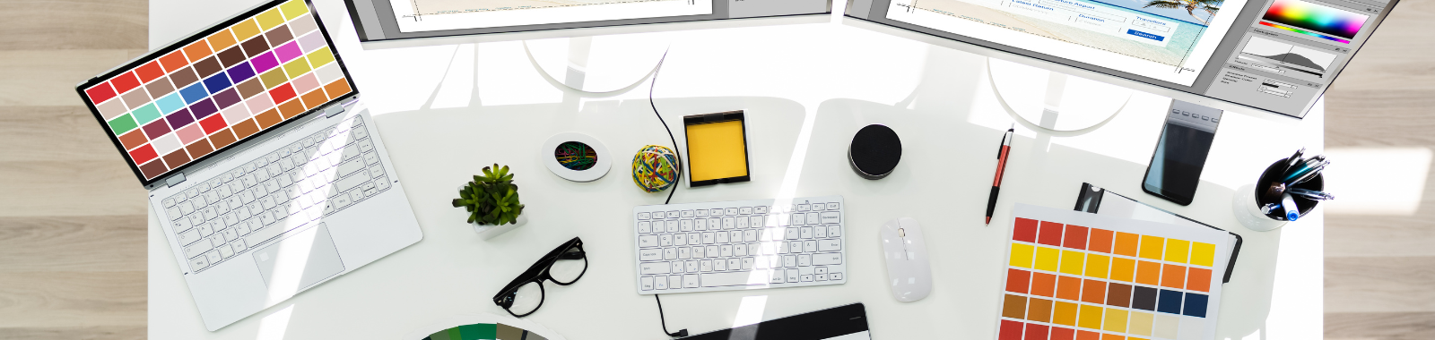 A desk with a laptop , tablet , phone , glasses , and other items on it.