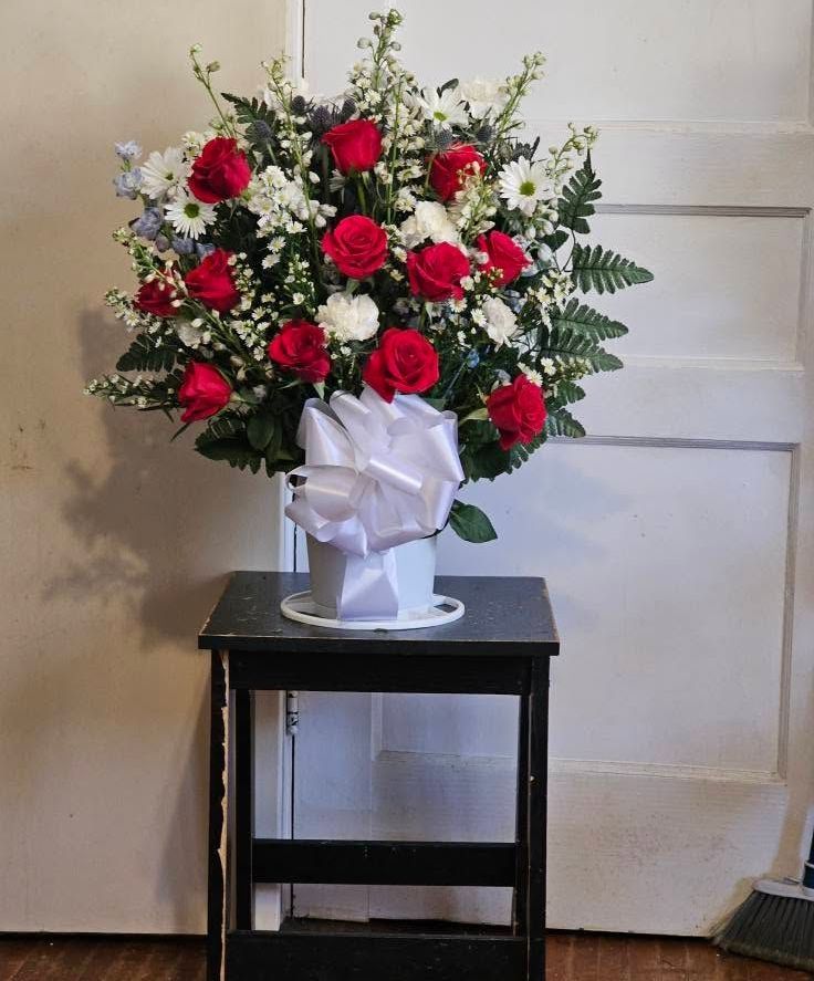 A vase filled with red roses and white daisies