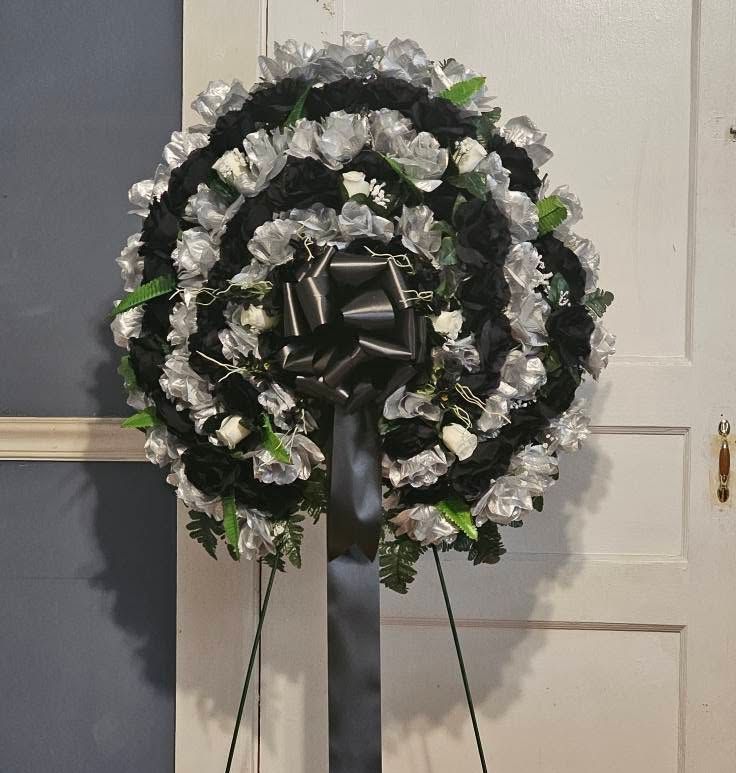 A black and silver wreath with a black bow