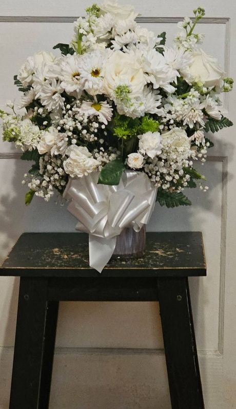 A vase filled with white flowers is sitting on a small table.