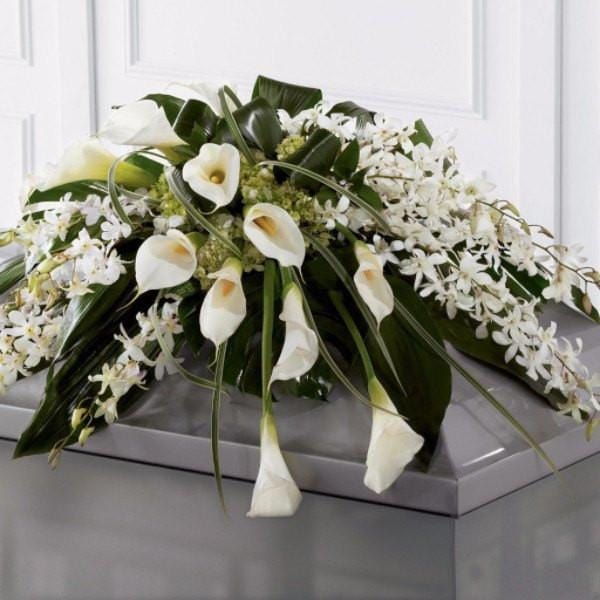 A coffin with white flowers and greenery on it