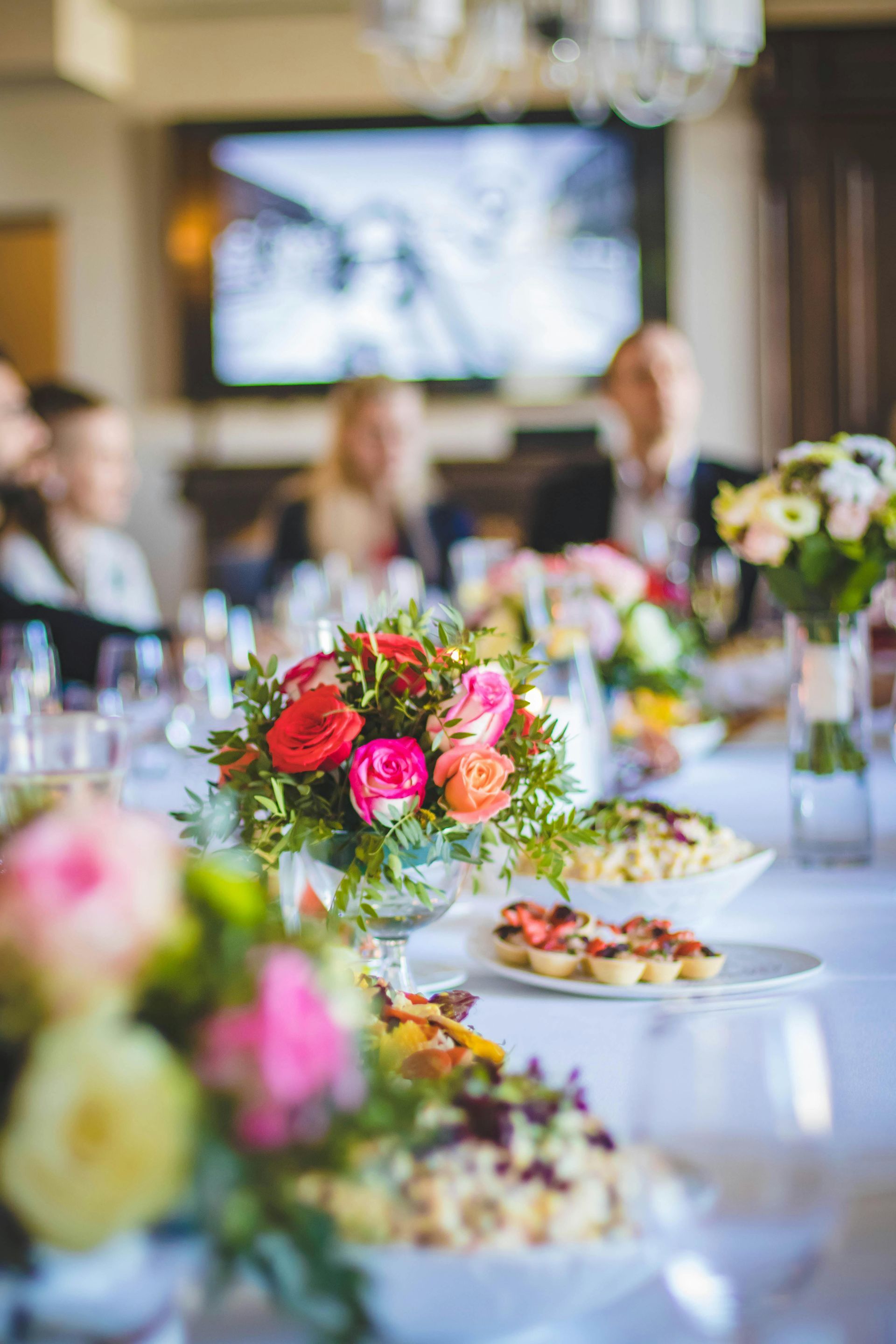 A long table with plates of food and flowers on it.