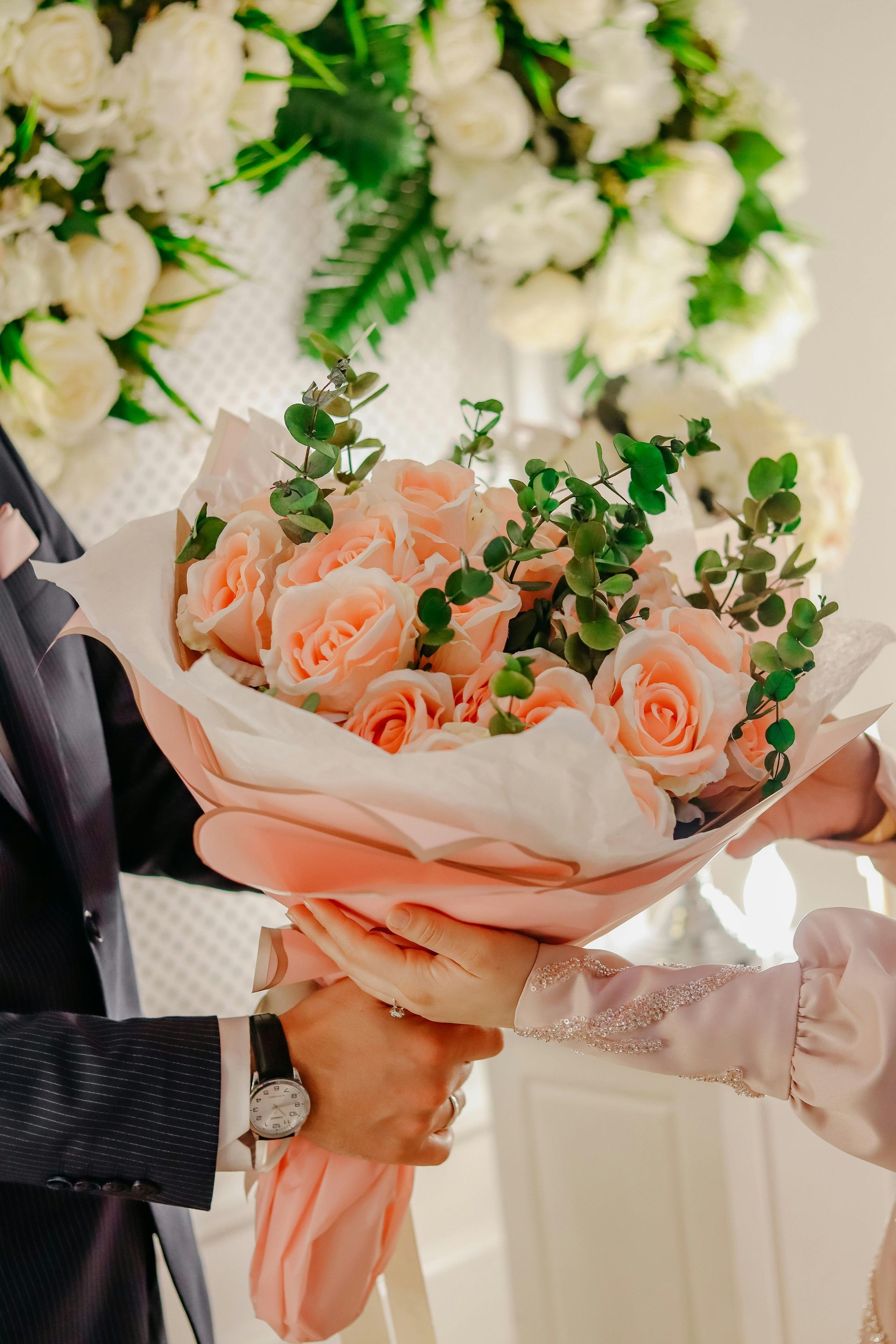 A man is holding a bouquet of pink roses in his hands.