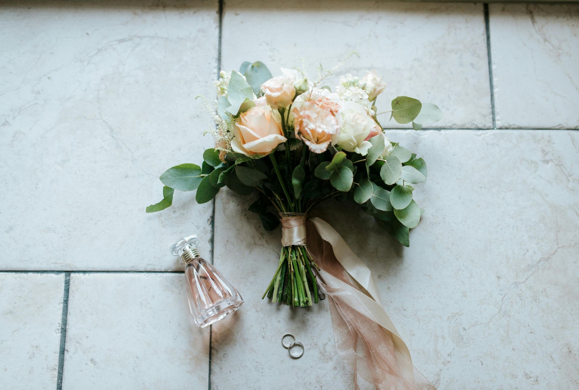 A bouquet of flowers and a bottle of perfume are on the floor.
