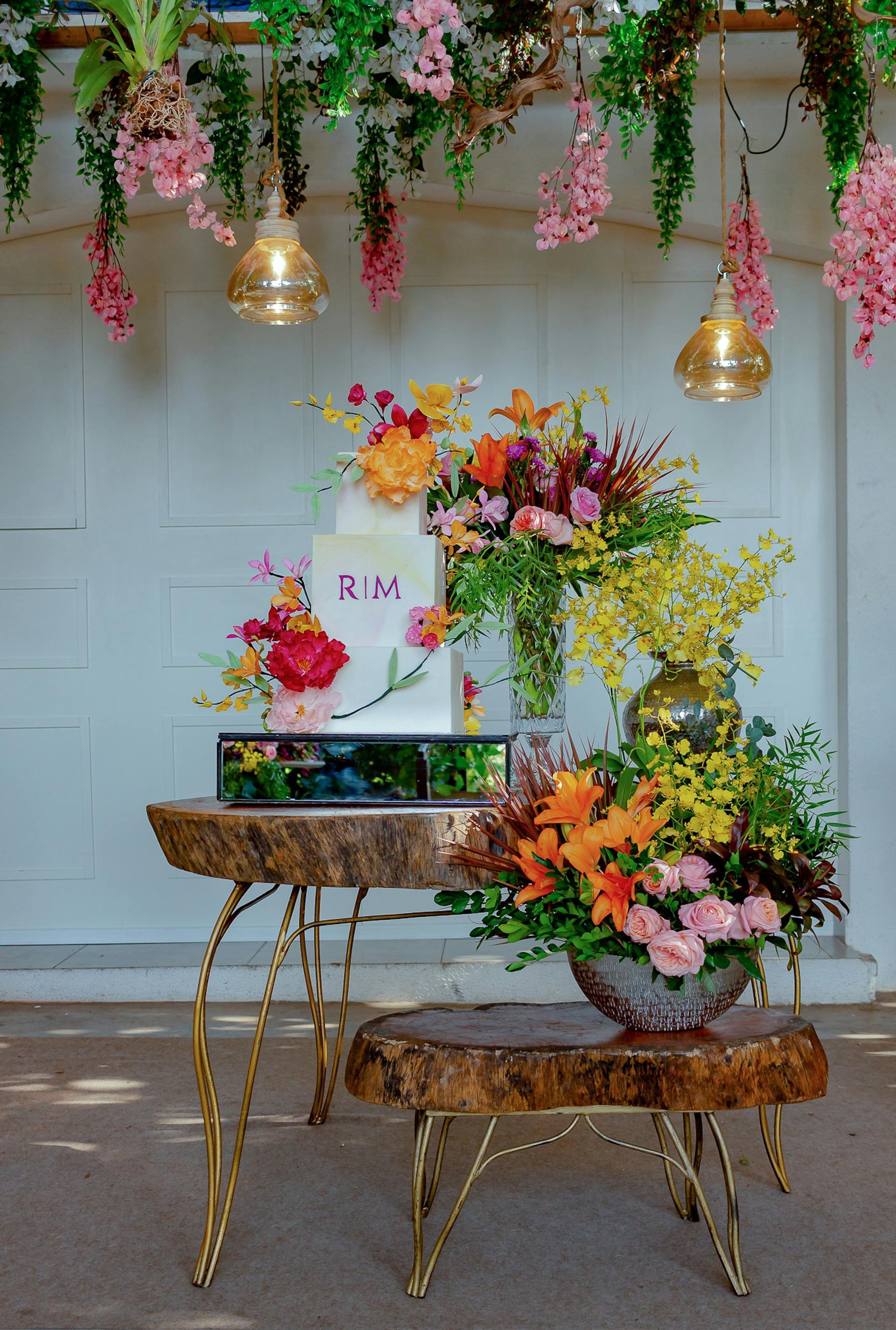 A table with a cake and vases of flowers on it.